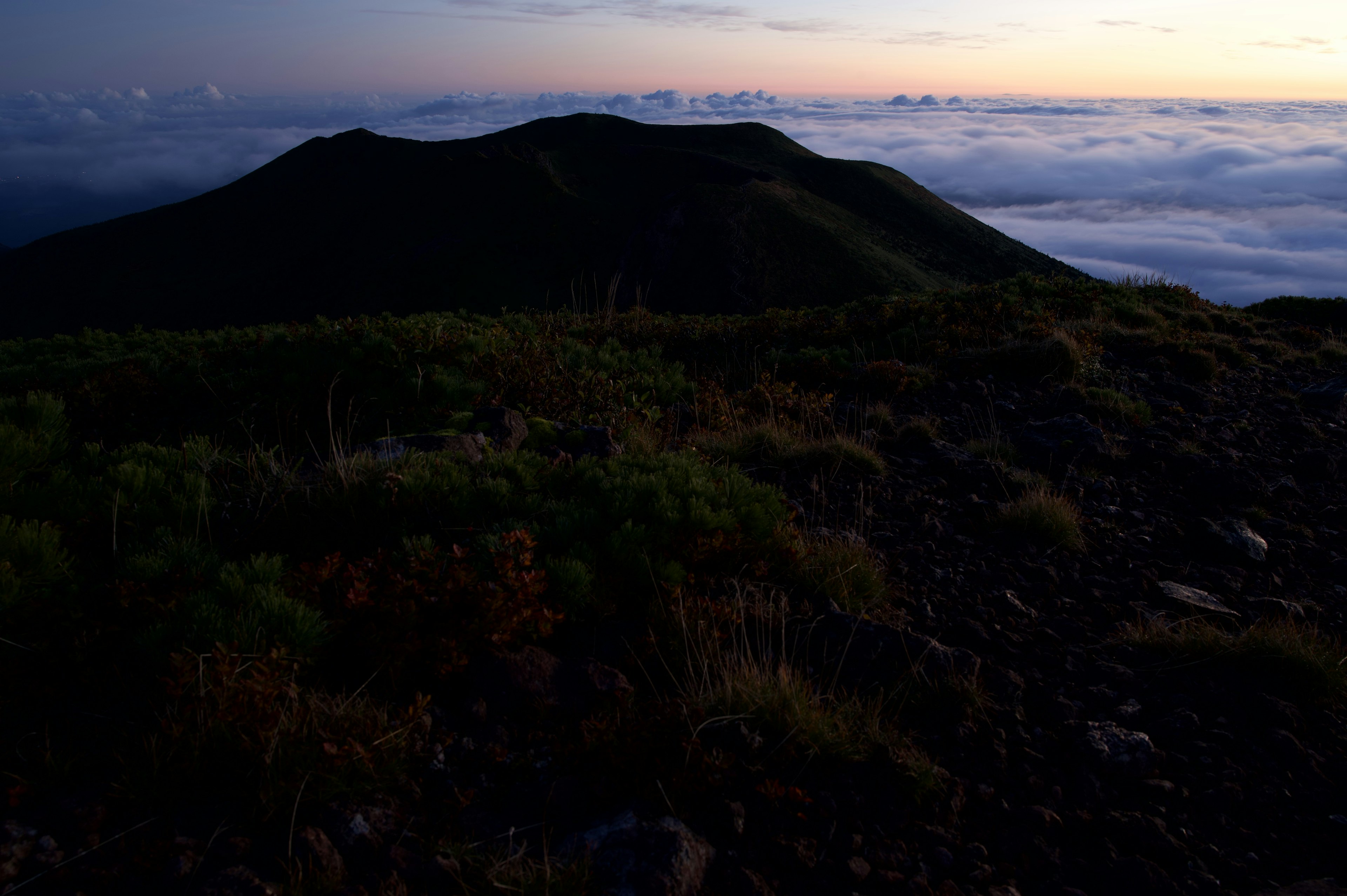 Siluet gunung saat matahari terbenam di atas lautan awan