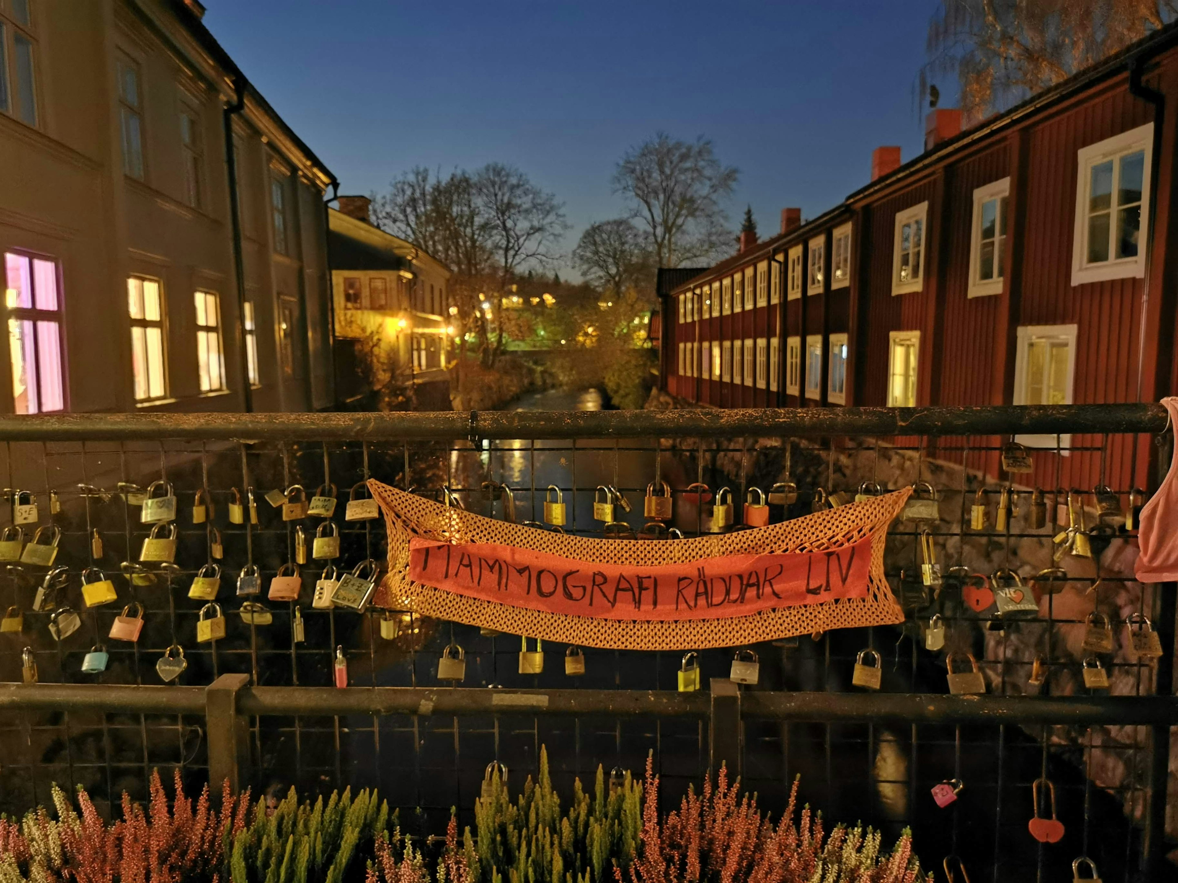 Love locks hanging on a bridge with a message banner in a quaint town at night