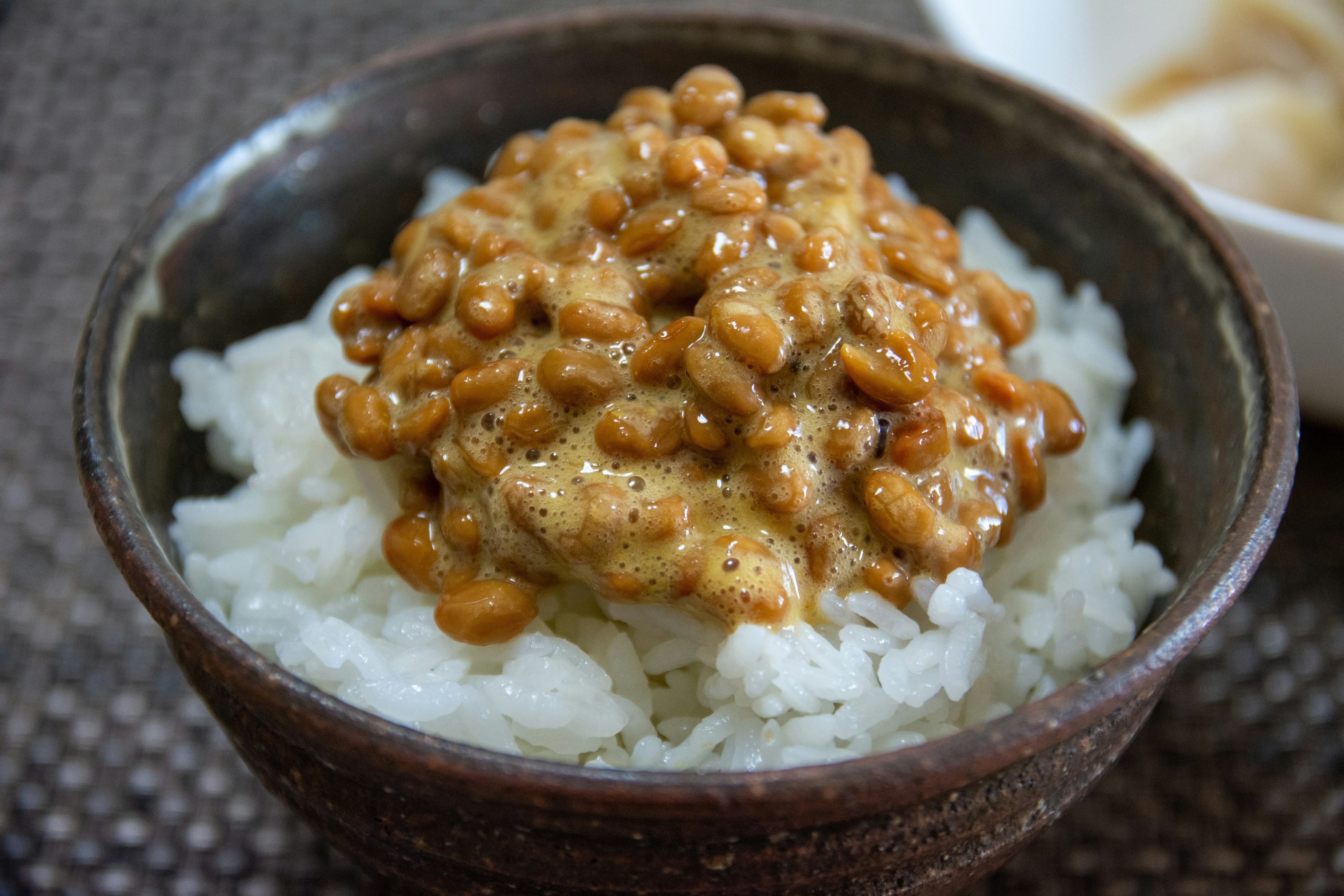 A bowl of rice topped with natto in a ceramic dish