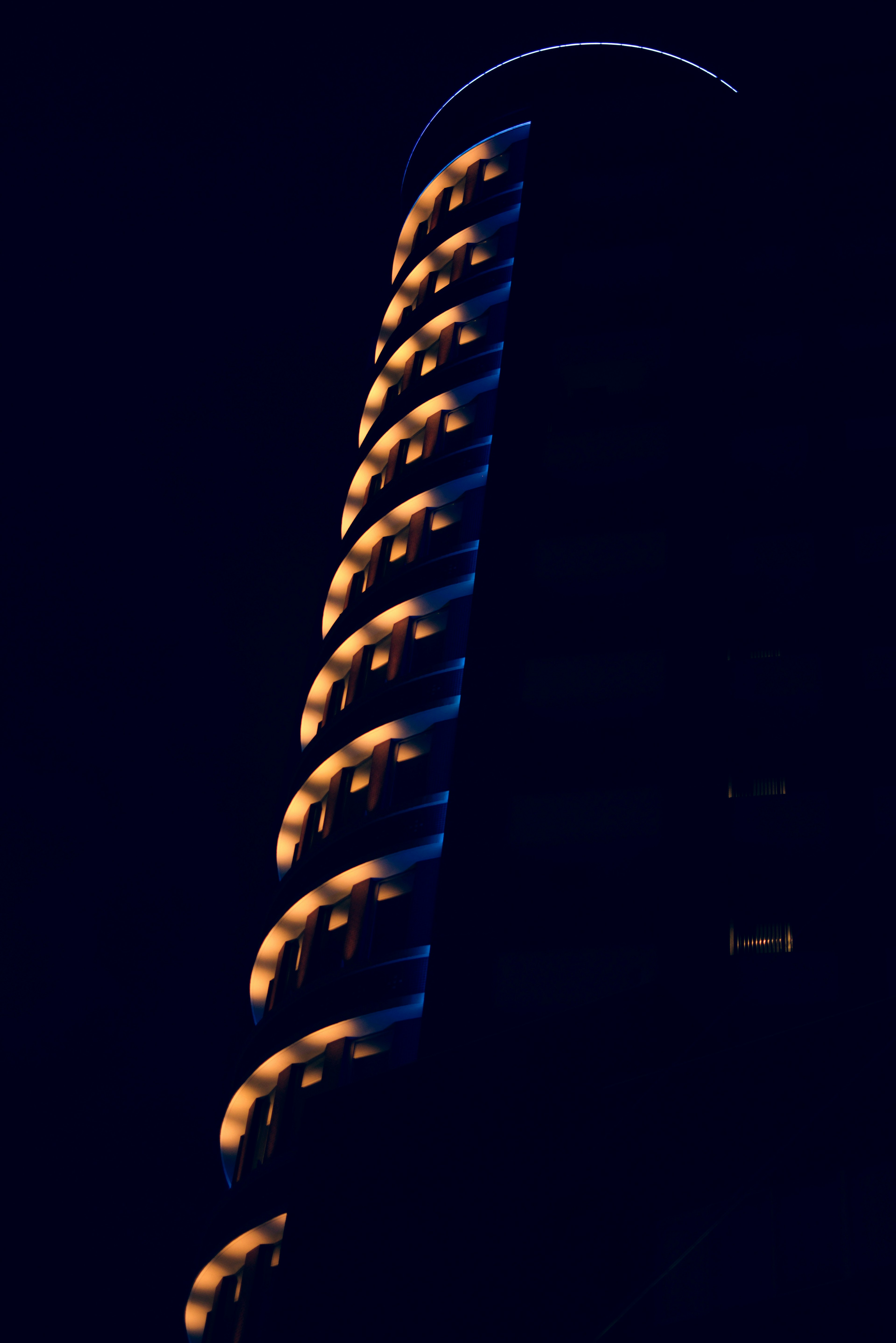 A section of a spiraling building illuminated against a dark background