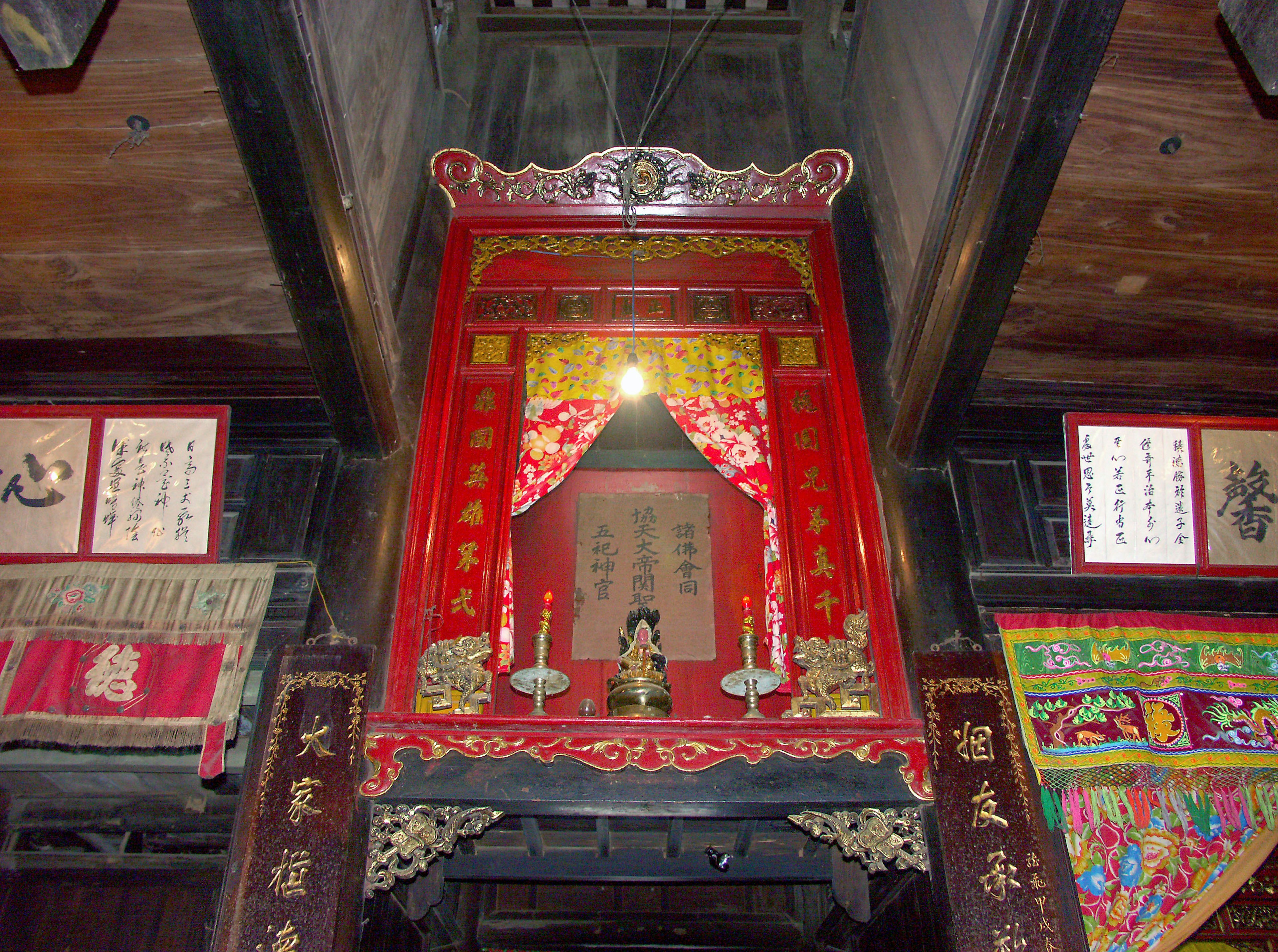 Interior ruangan dengan altar dekoratif merah dan kaligrafi Cina tradisional