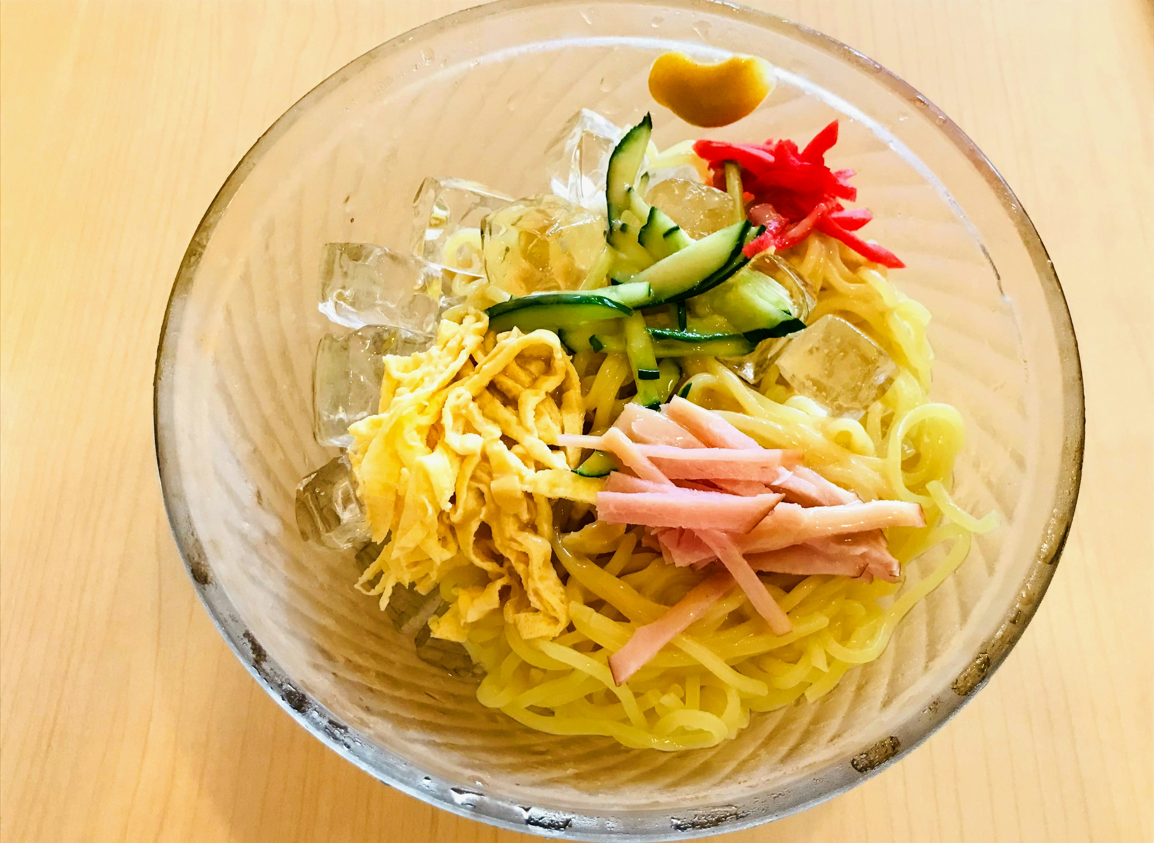 Chilled noodles dish featuring sliced cucumber, egg, ham, pickled ginger, and wasabi