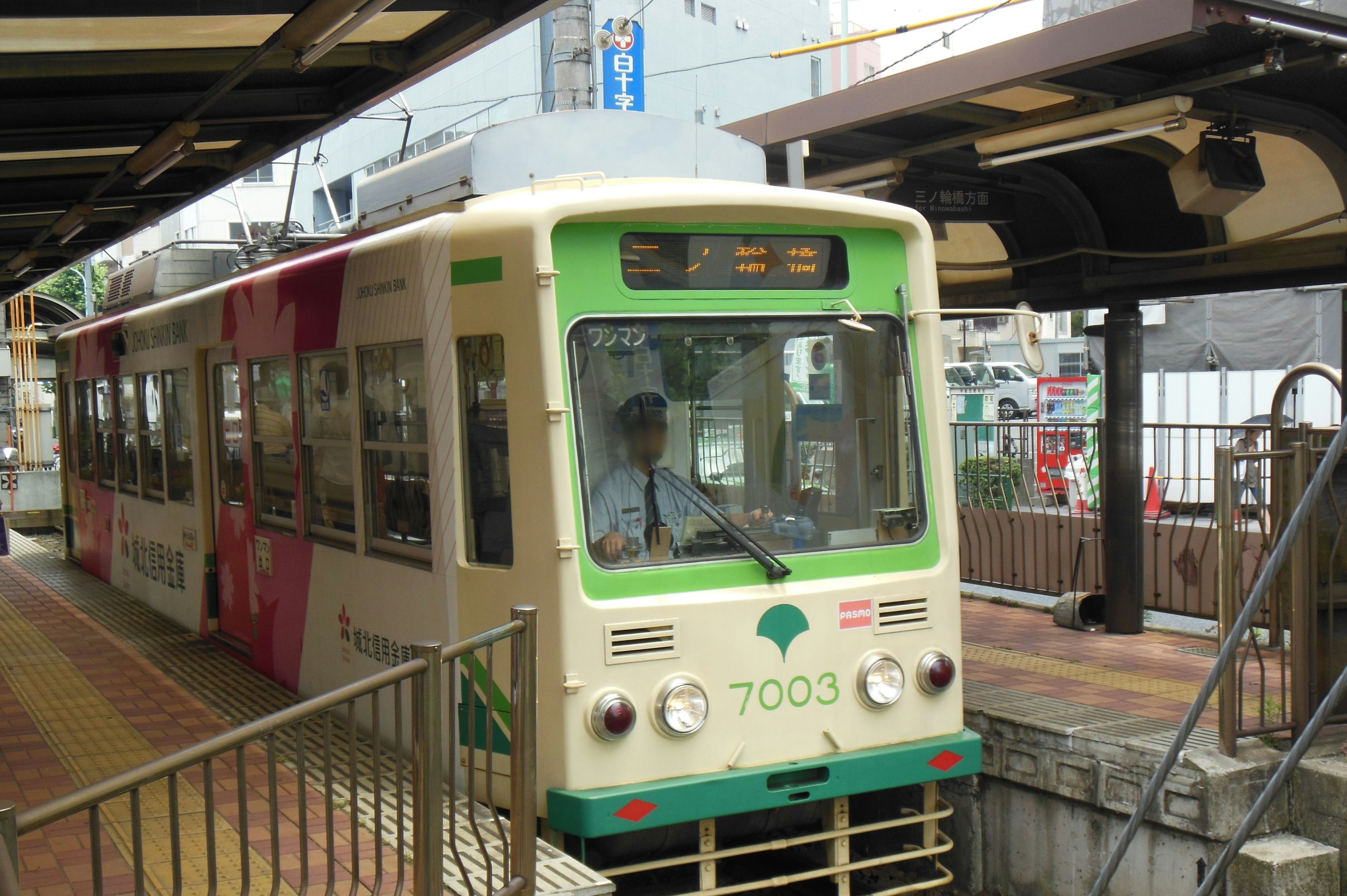 Green and white tram is stopped at the station