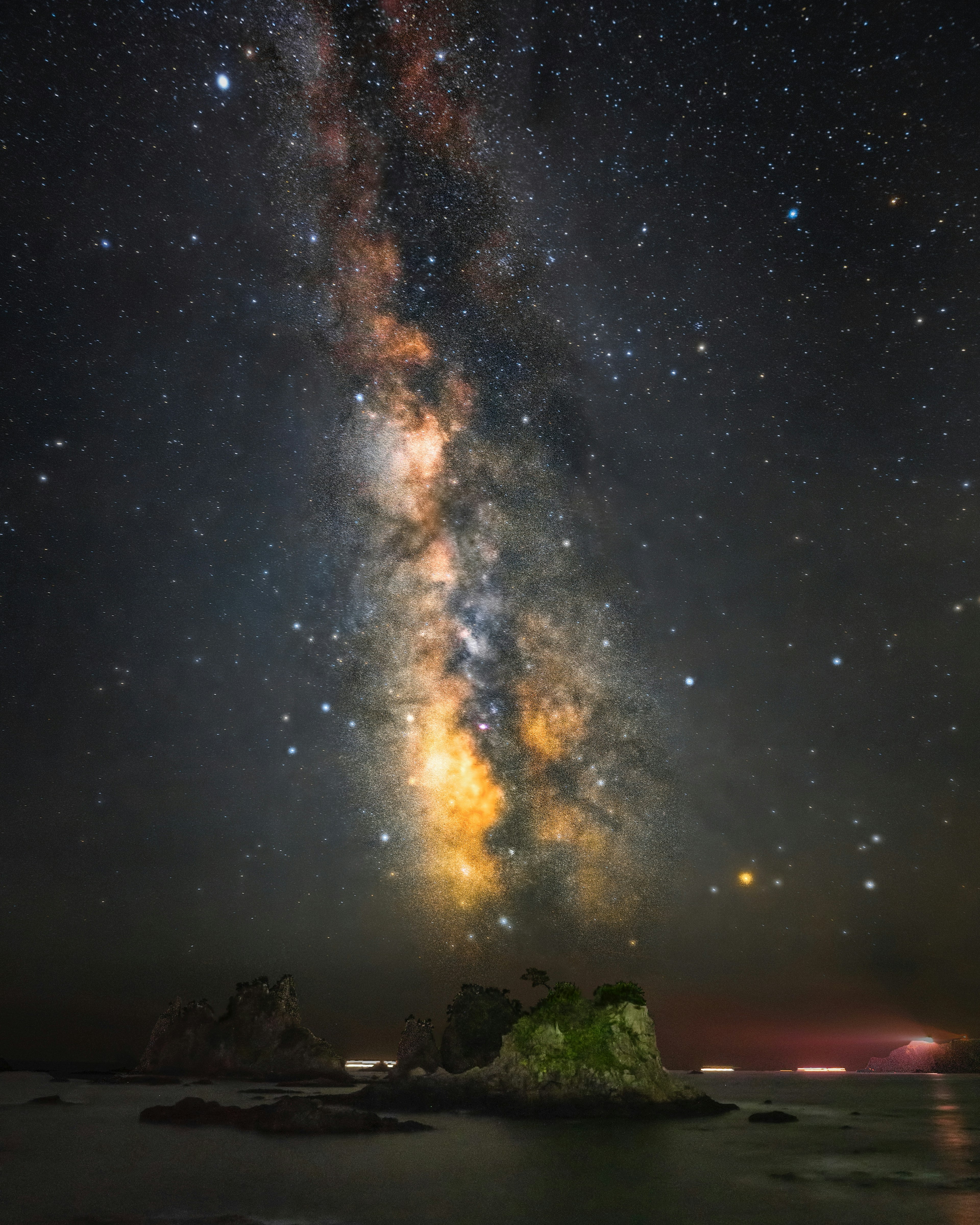 星空の下の海に浮かぶ岩と天の川の美しい景色