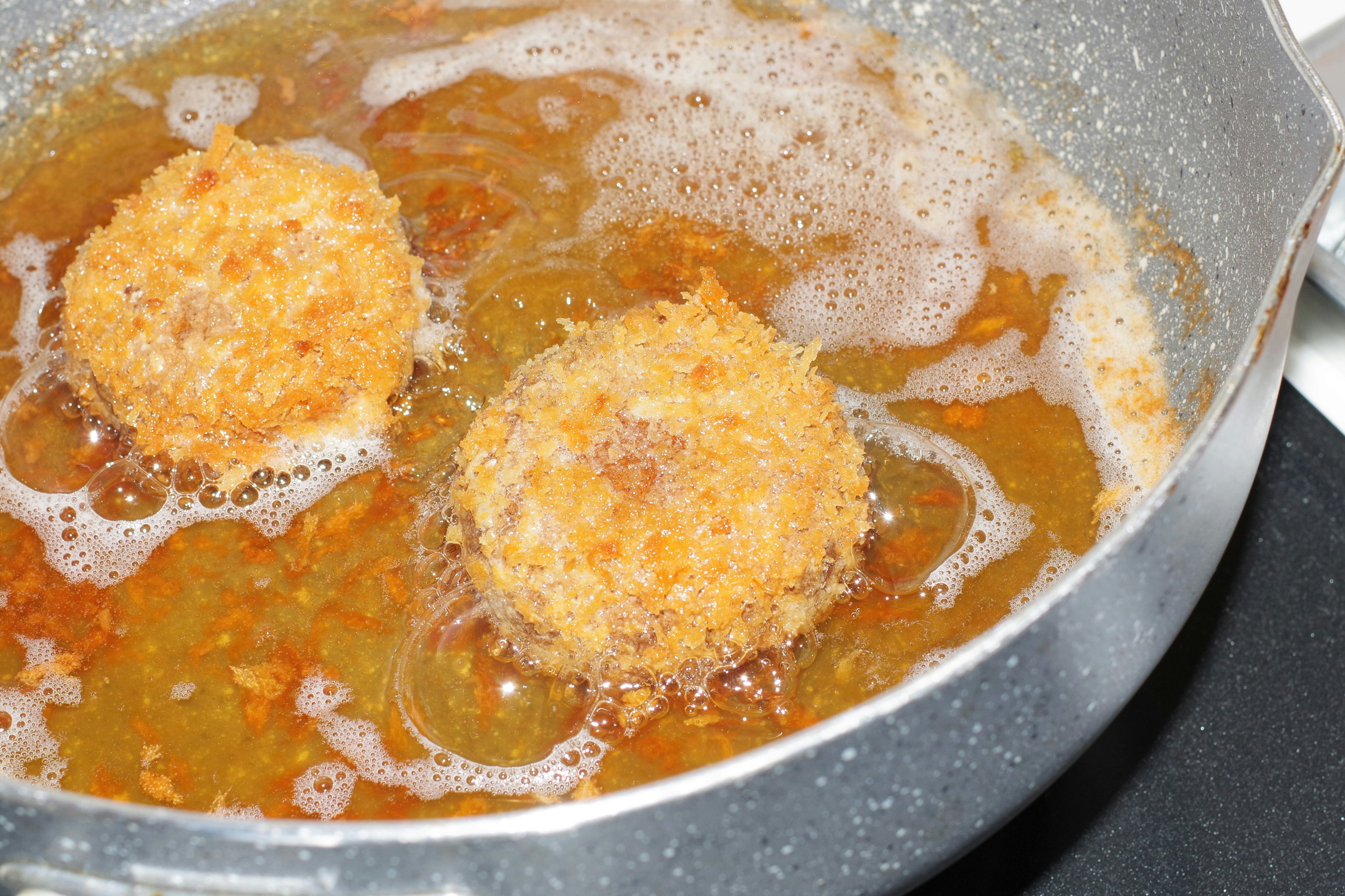 Runde Kroketten, die in sprudelndem Öl frittieren