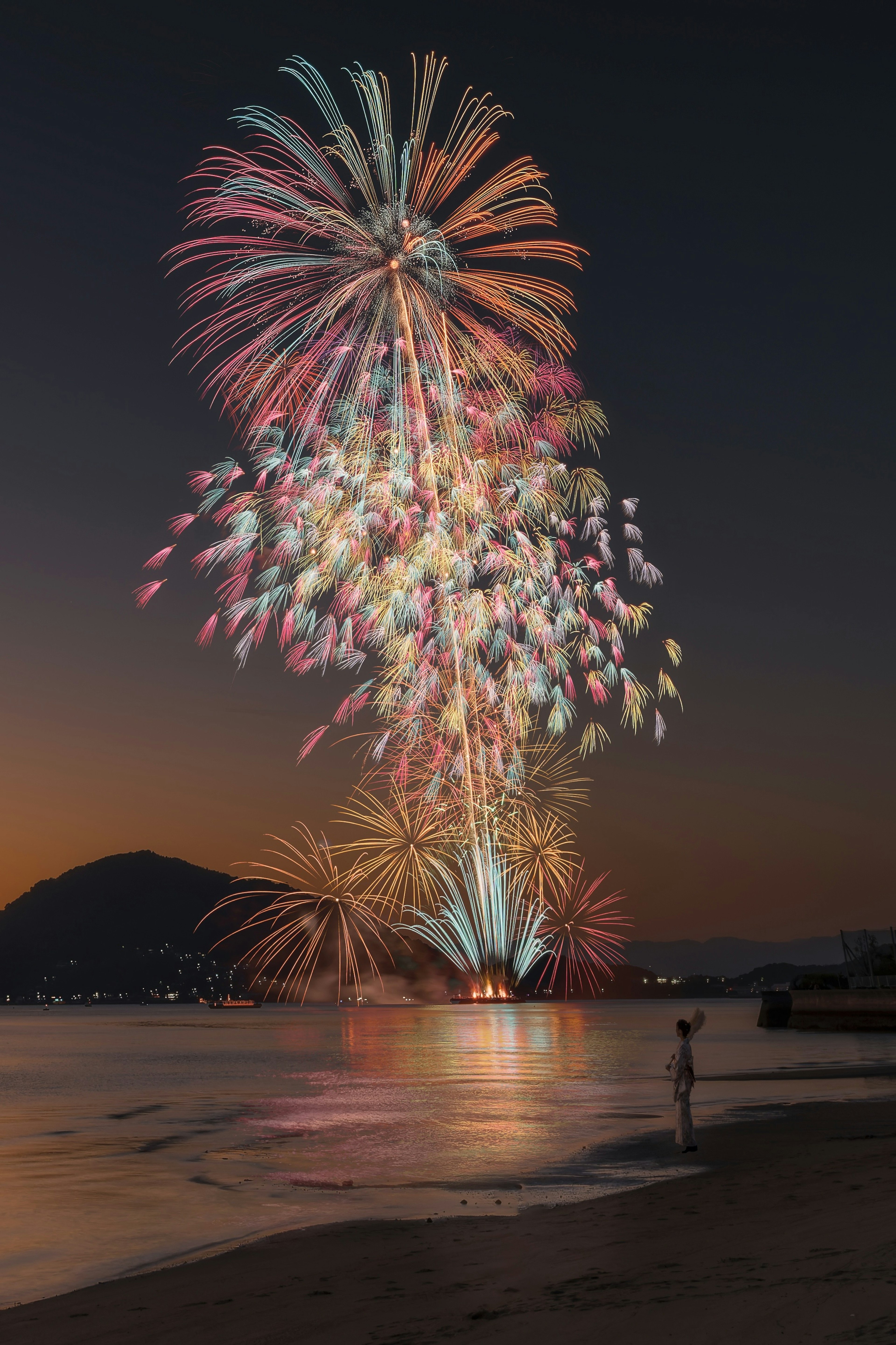 Espectáculo de fuegos artificiales coloridos sobre la playa al anochecer