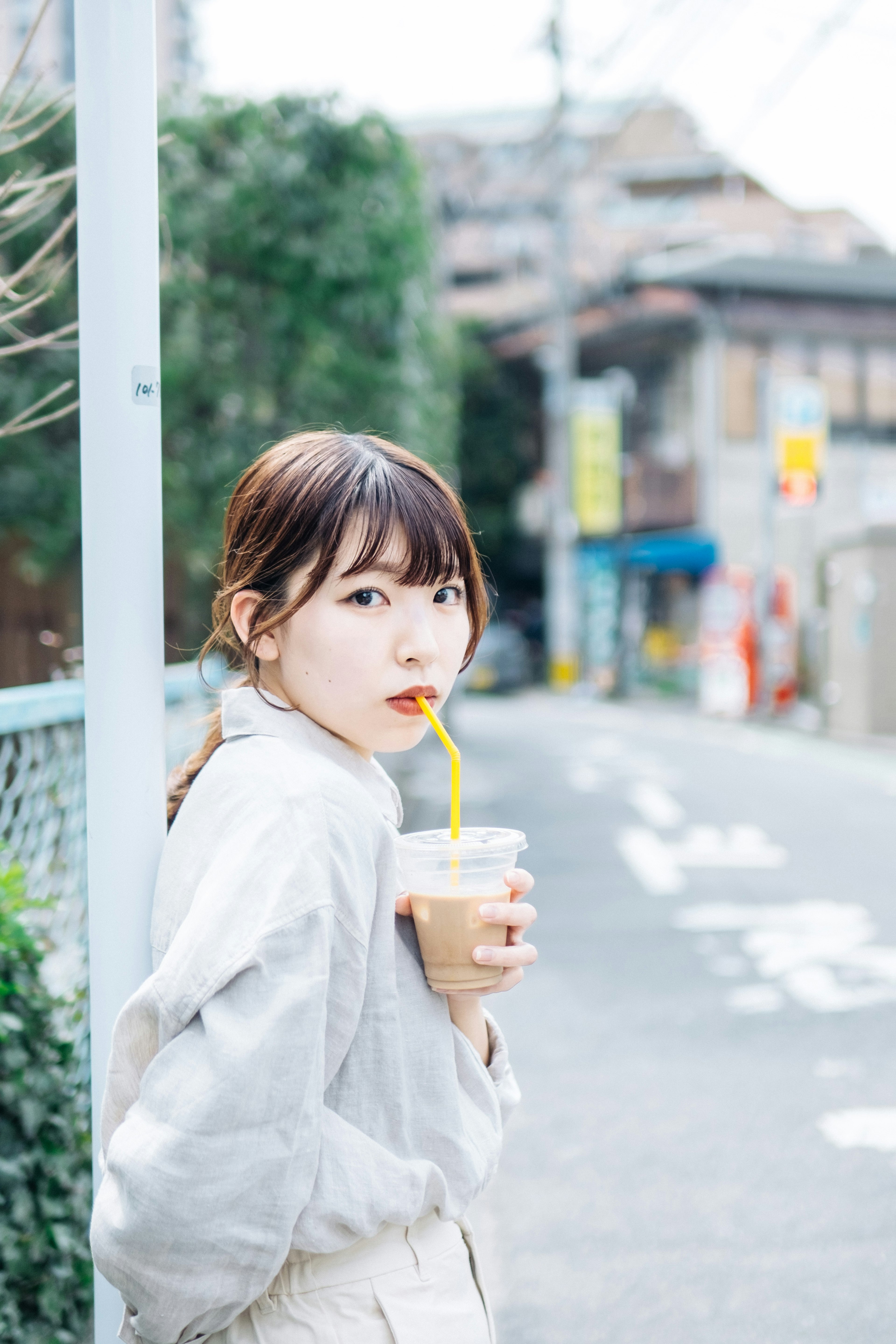 A woman looking back while holding a drink on a city street