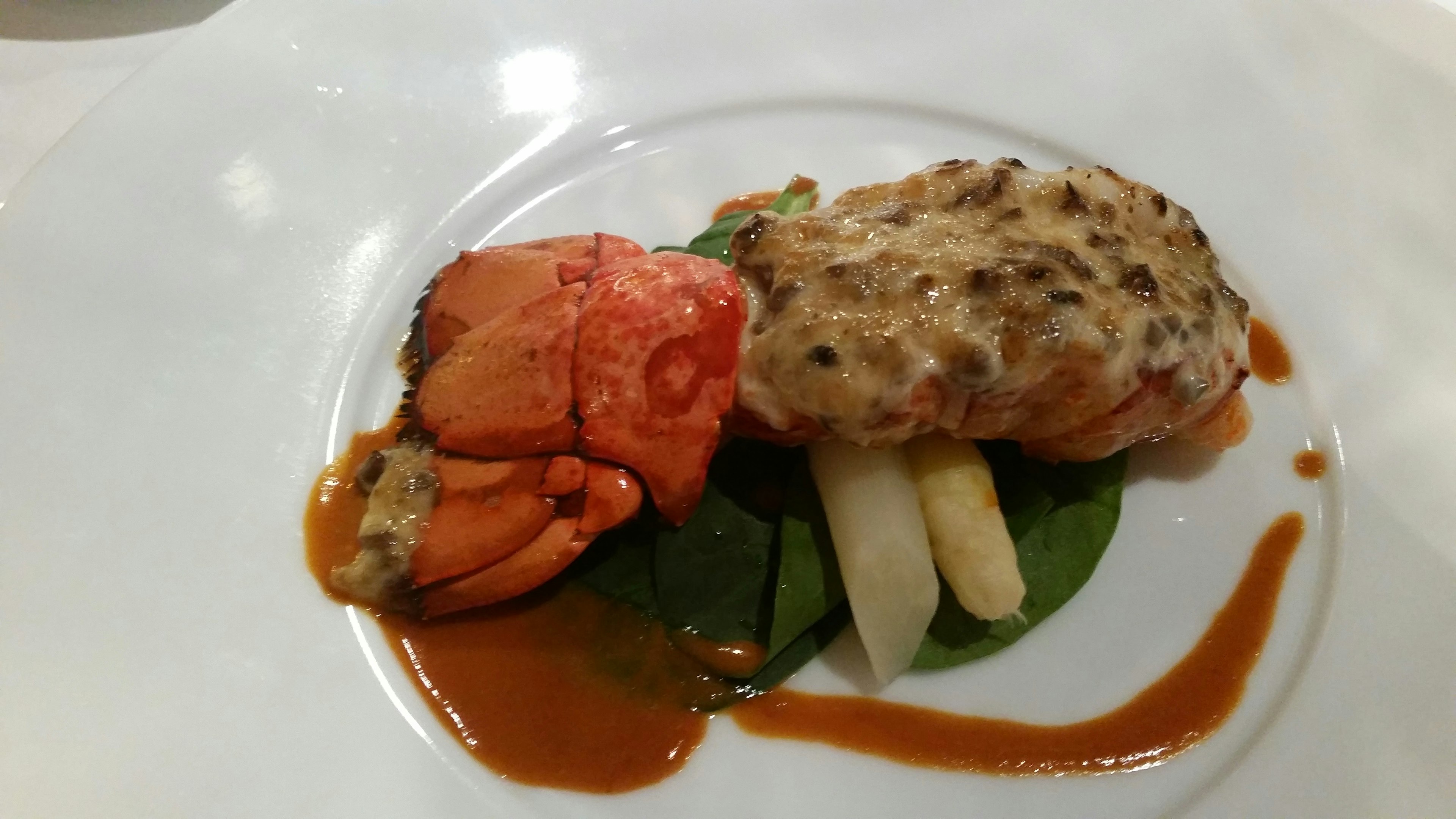 Piring hidangan gourmet dengan salmon asparagus putih bayam dan saus