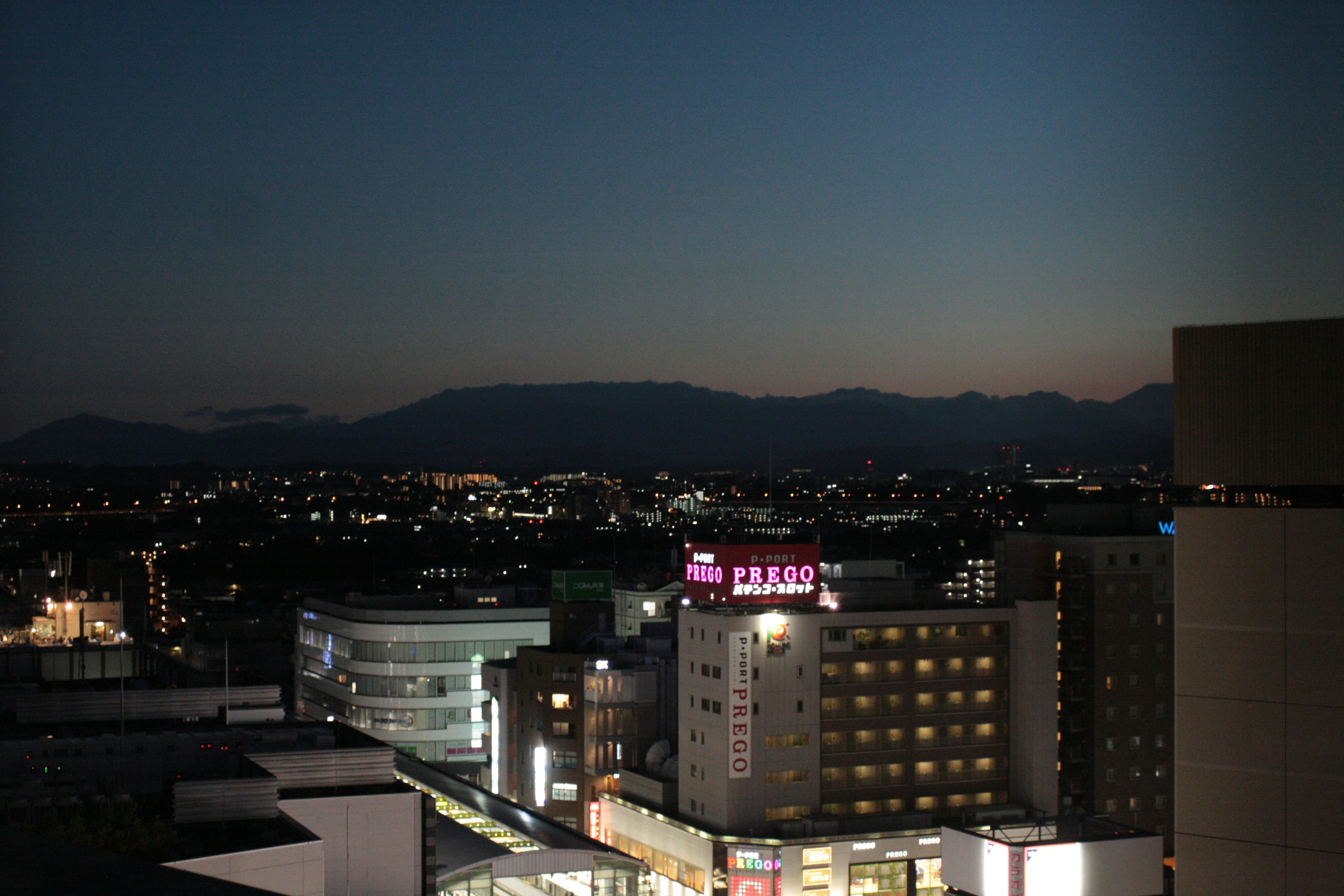 夜景の街並みと山々のシルエットが見える