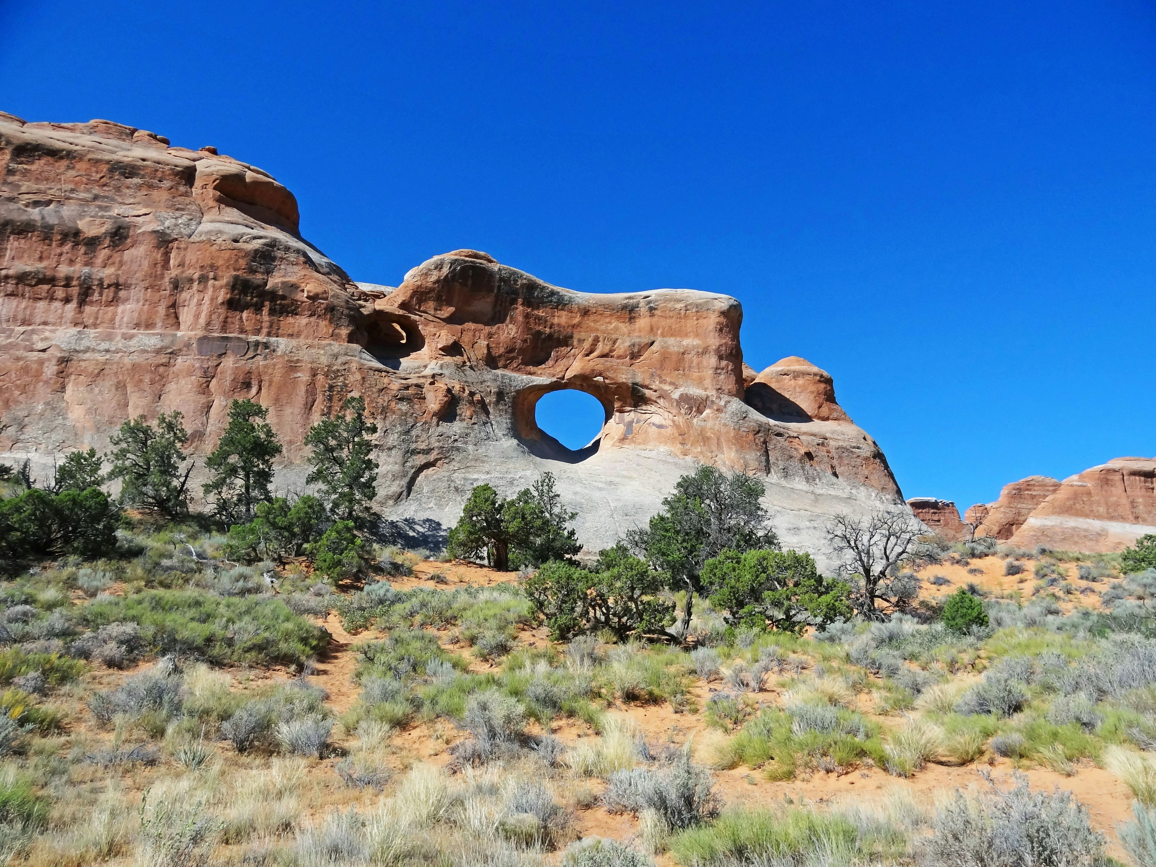 rock formation with a circular hole under a blue sky