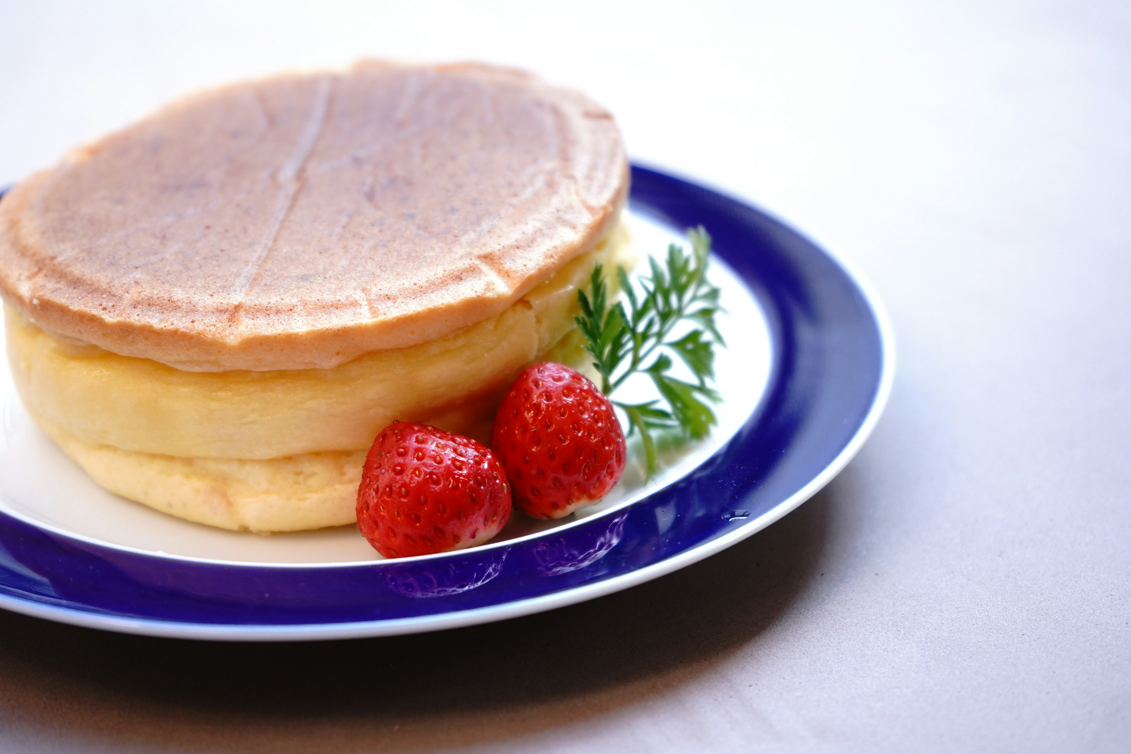 Fluffy pancakes served with strawberries on a plate