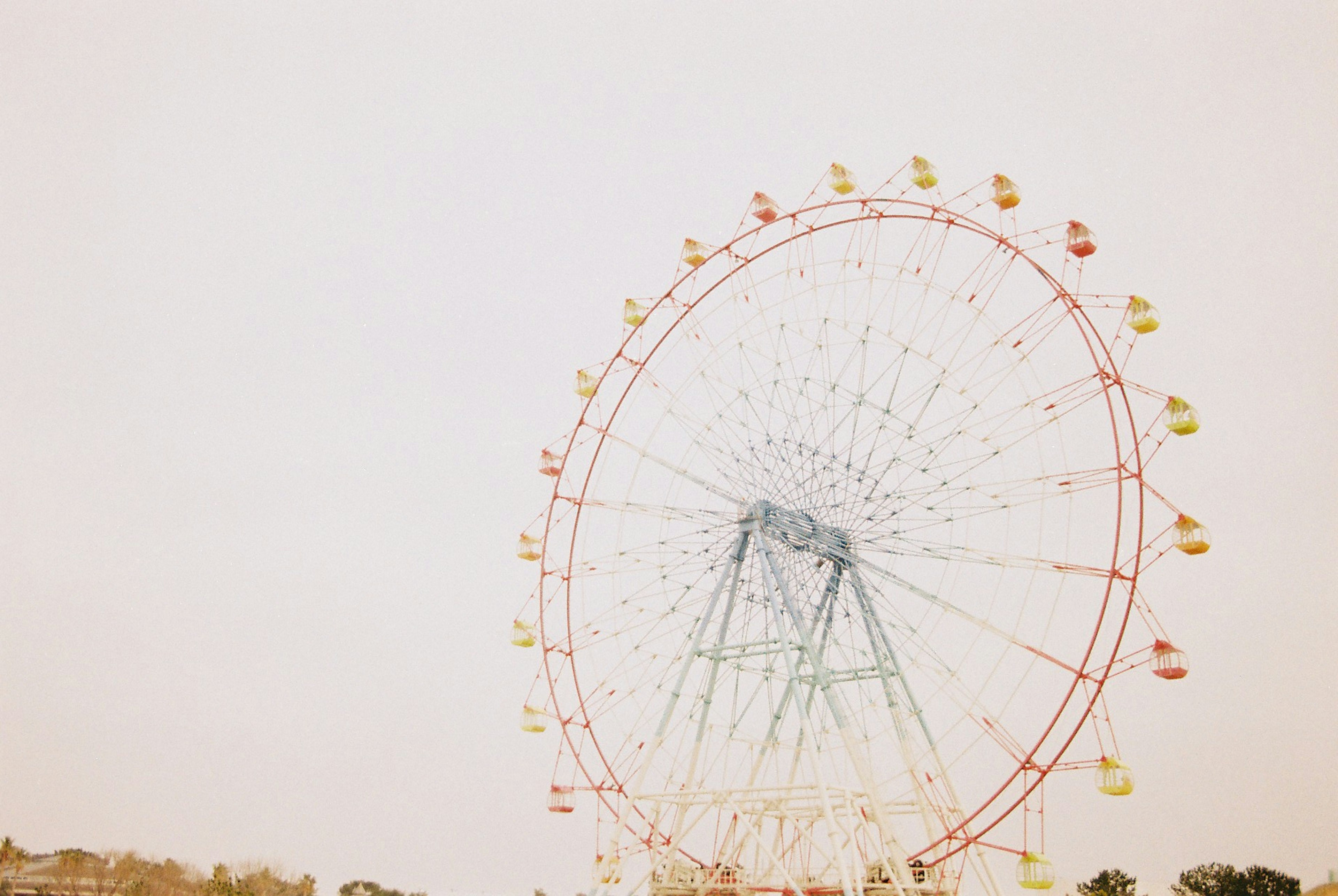 Riesenrad mit bunten Kapseln vor einem hellen Hintergrund