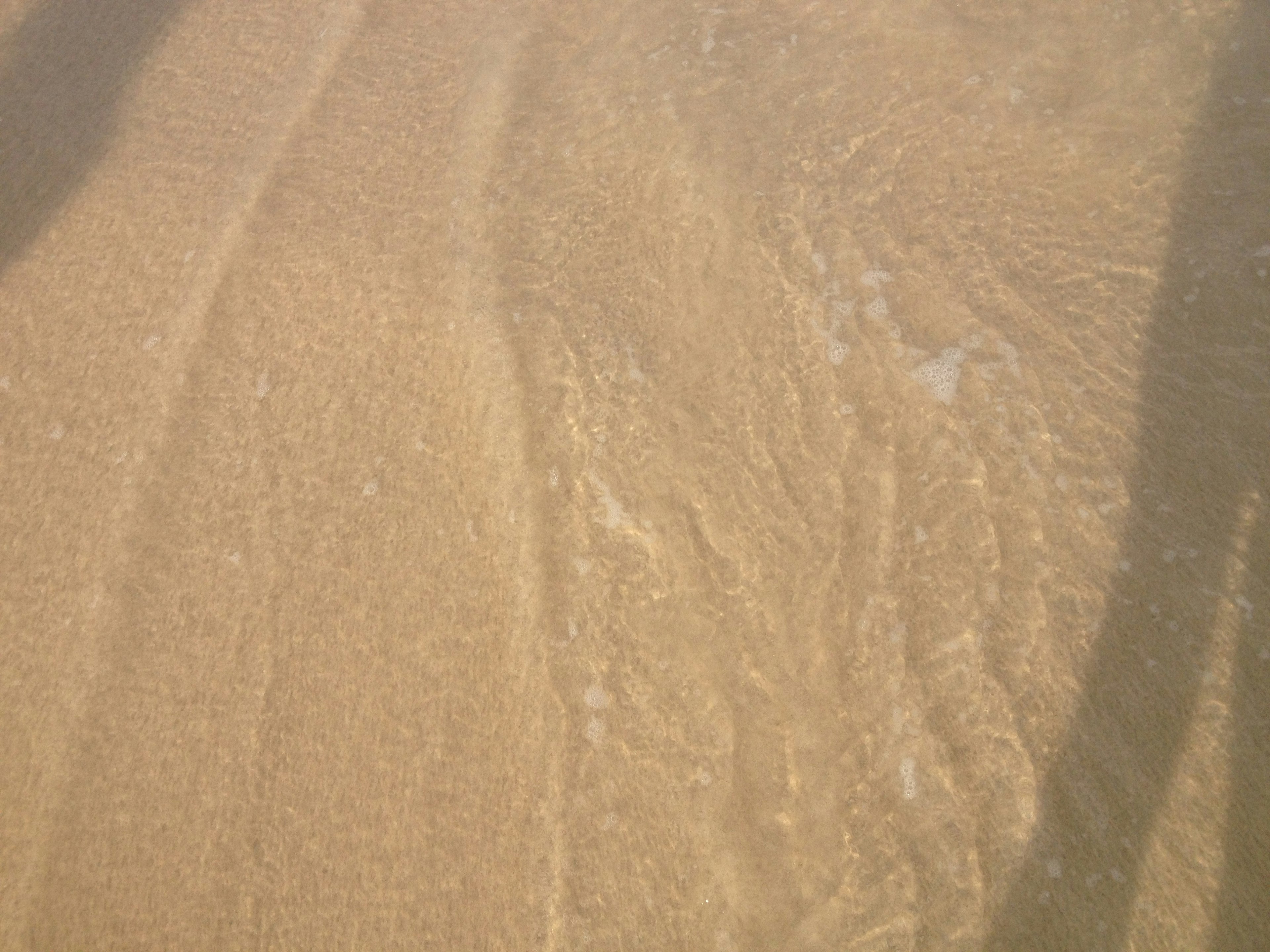 Image capturing the patterns of waves and water on a sandy beach