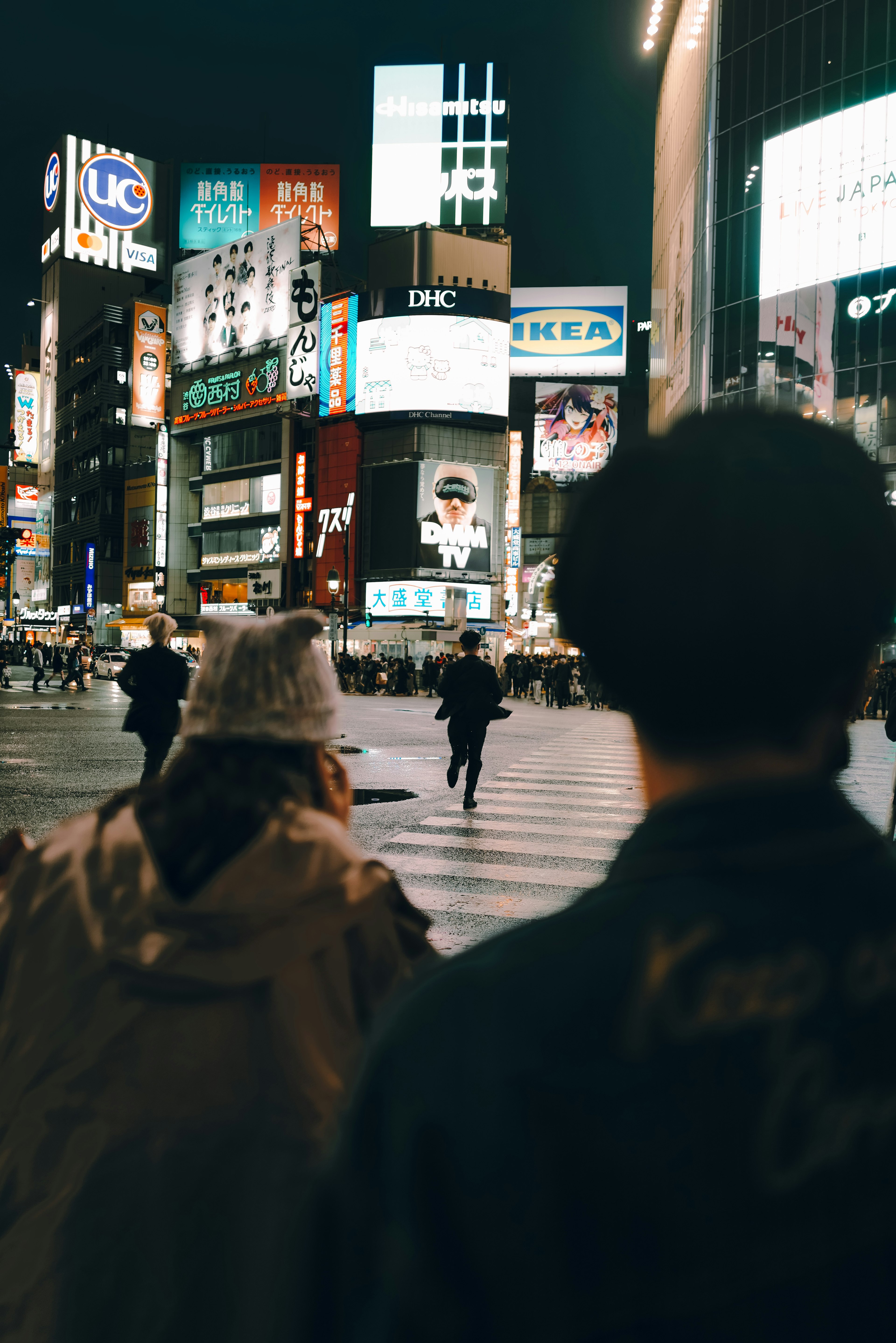 夜の繁華街で人々が交差点を渡る様子と明るい看板