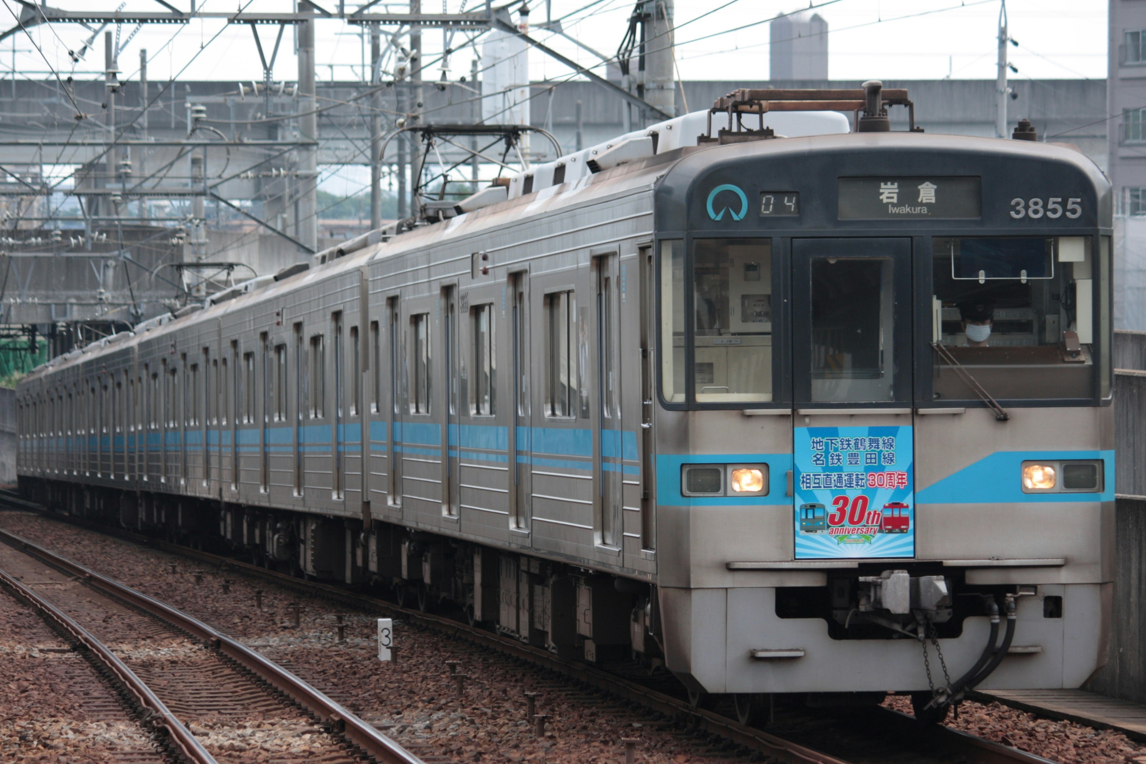 青いラインが特徴の日本の電車が線路に停車中