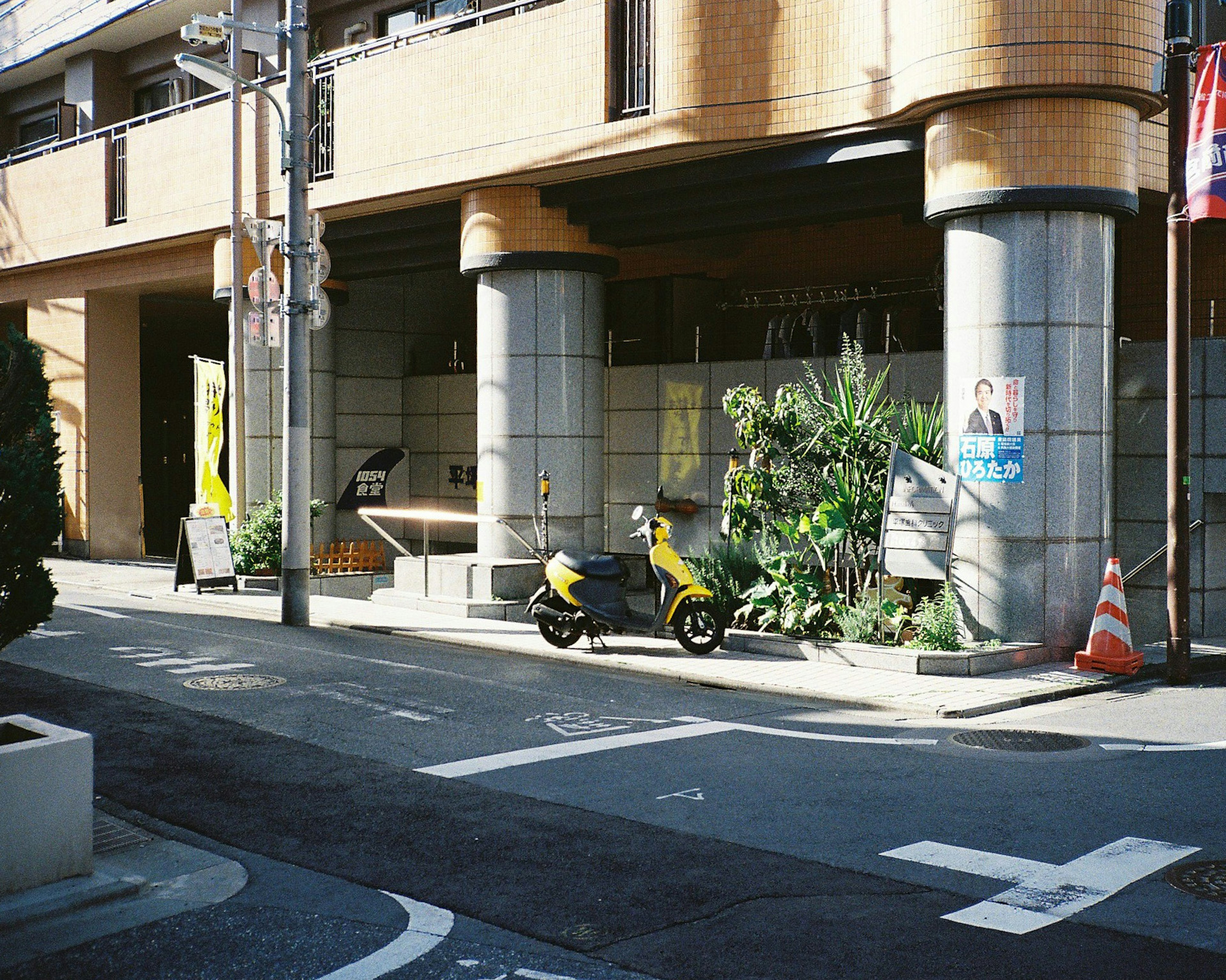 Street view featuring a building, a motorcycle, and greenery