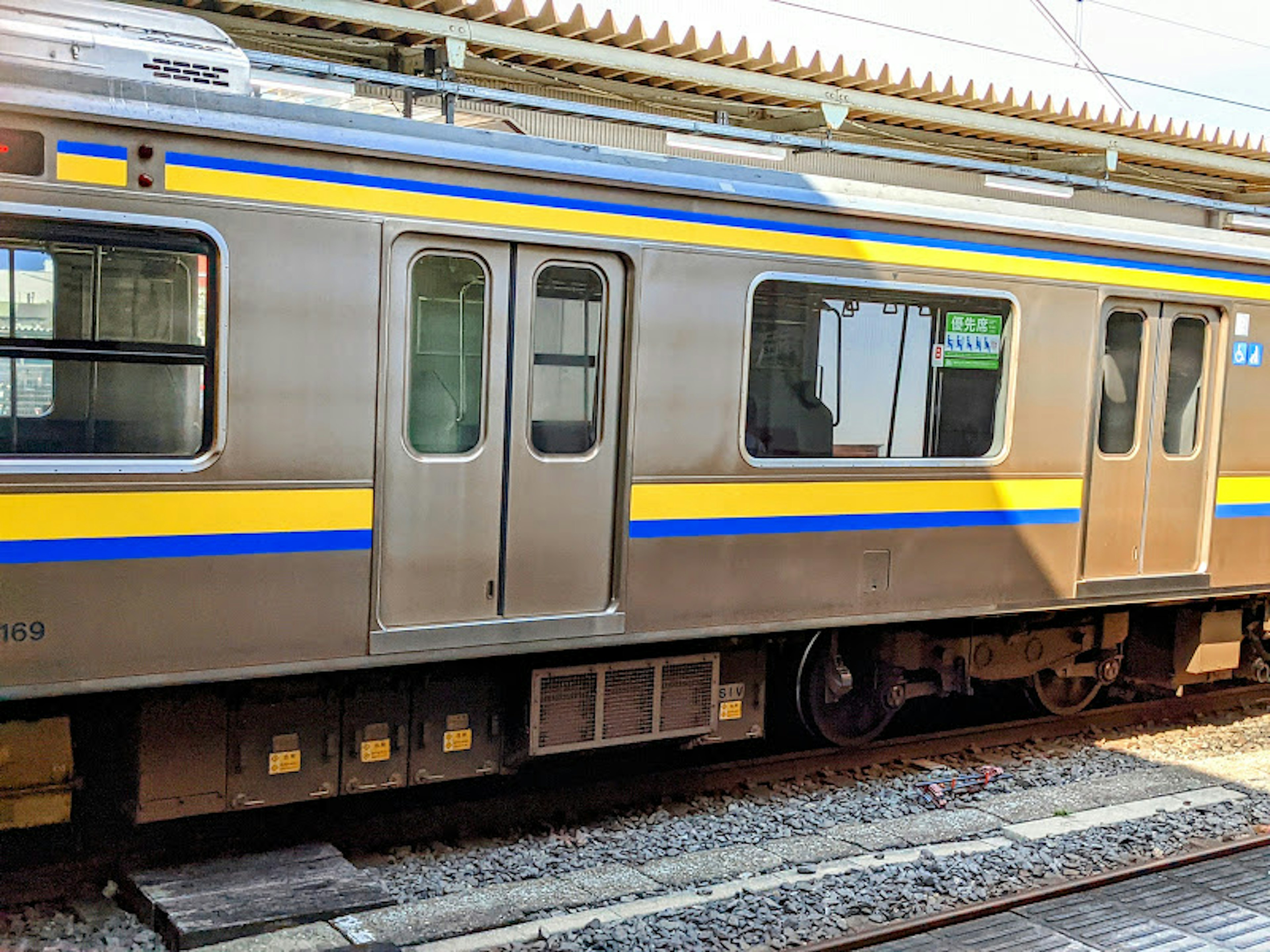 Silver train car side view featuring blue and yellow stripes