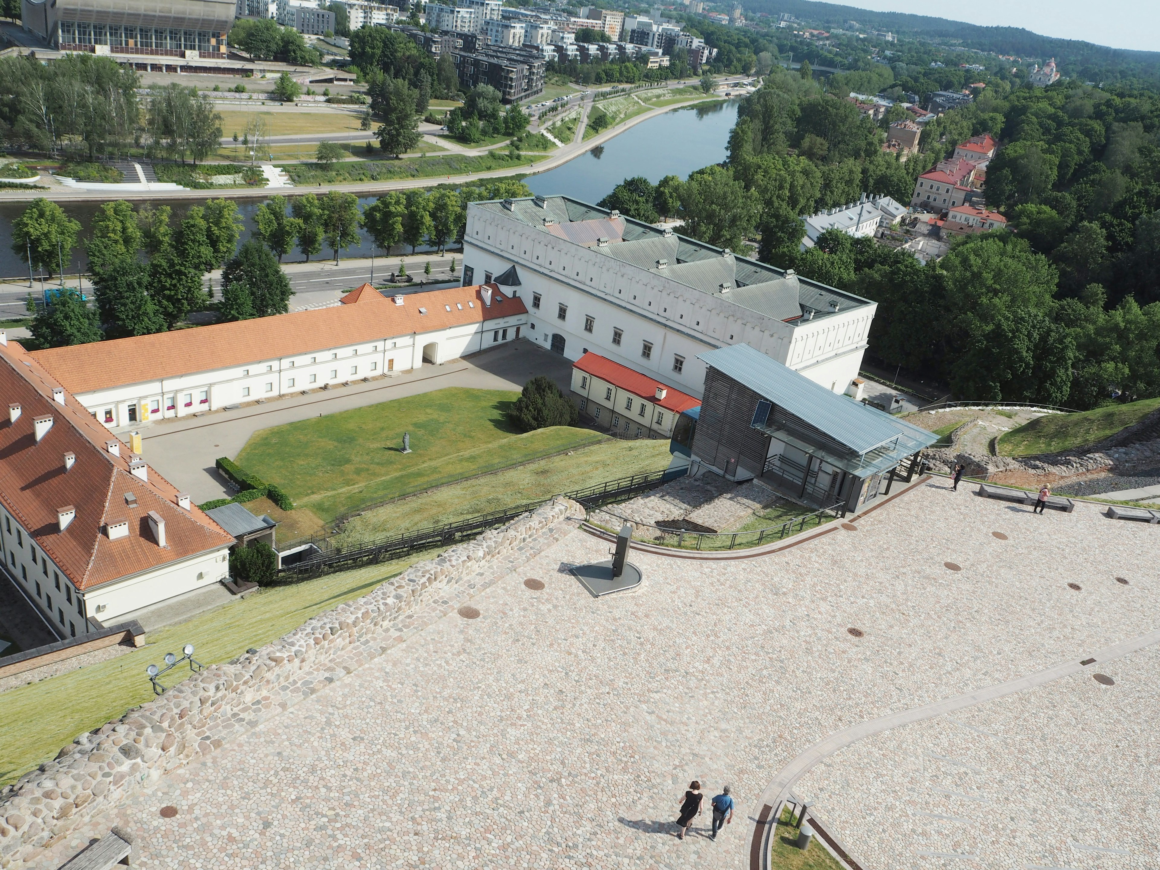 Aerial view of a historic building with a green lawn and river nearby