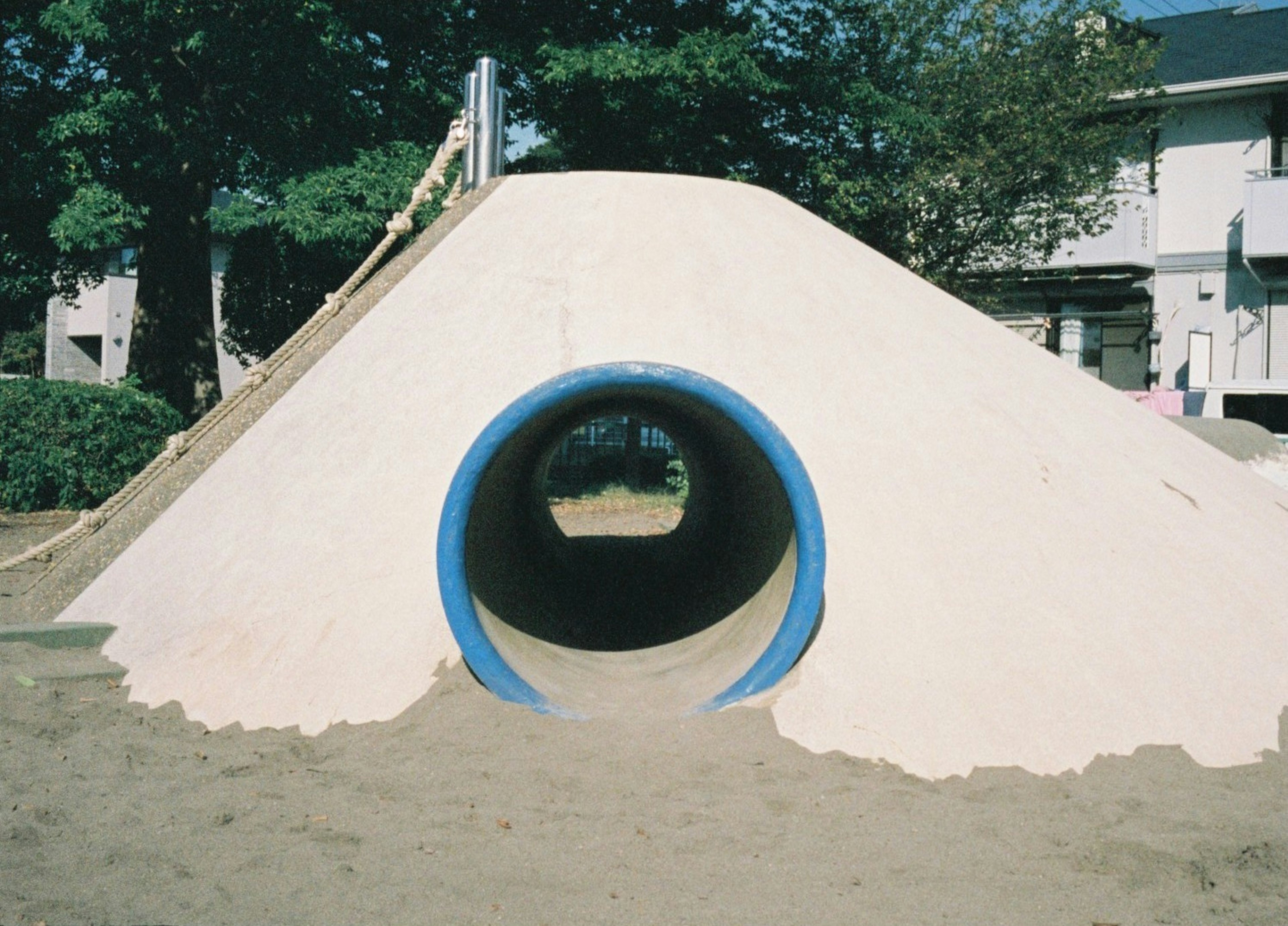 公園の遊具である青いトンネルのある砂の山