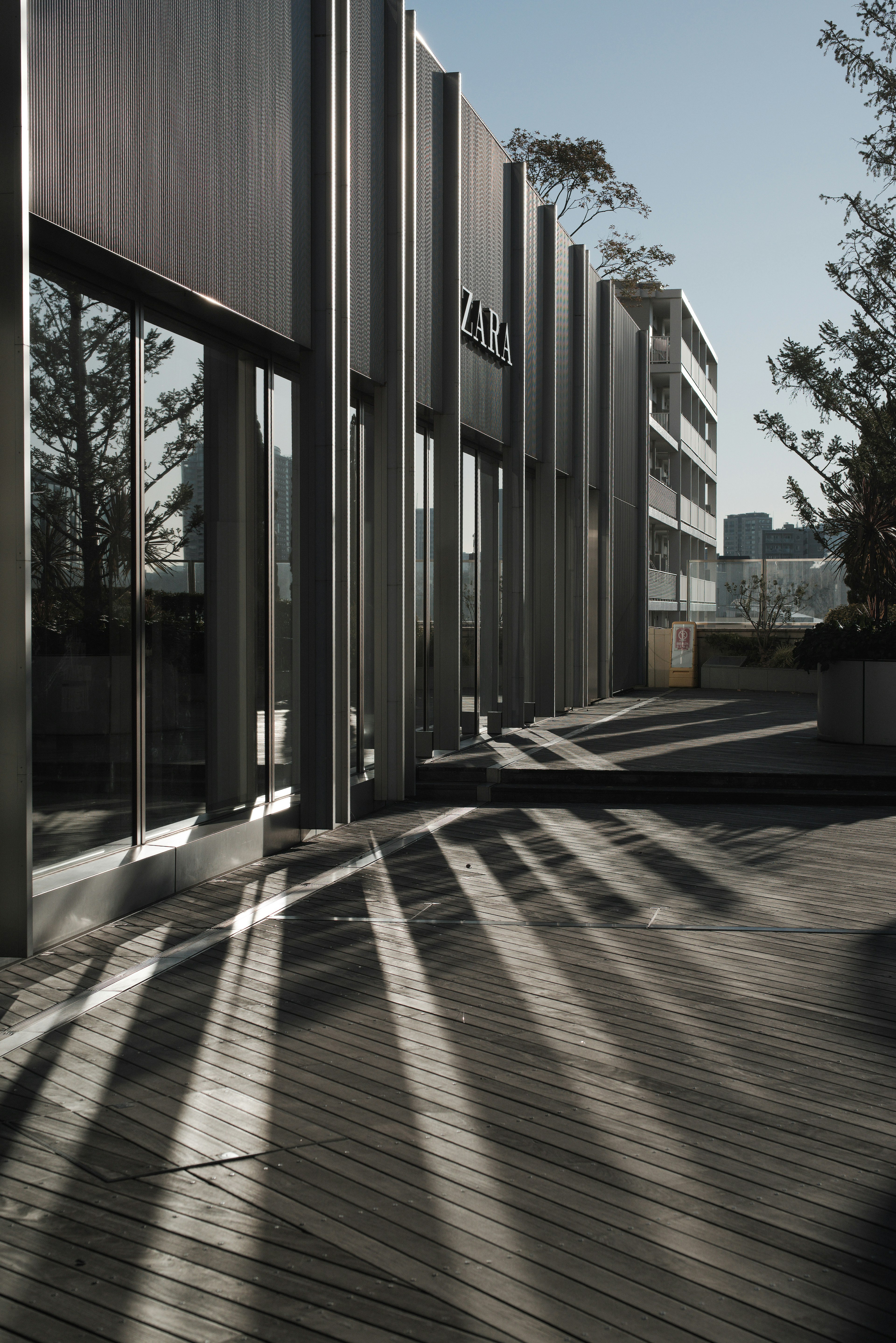 Exterior de un edificio moderno con sombras sobre una terraza de madera