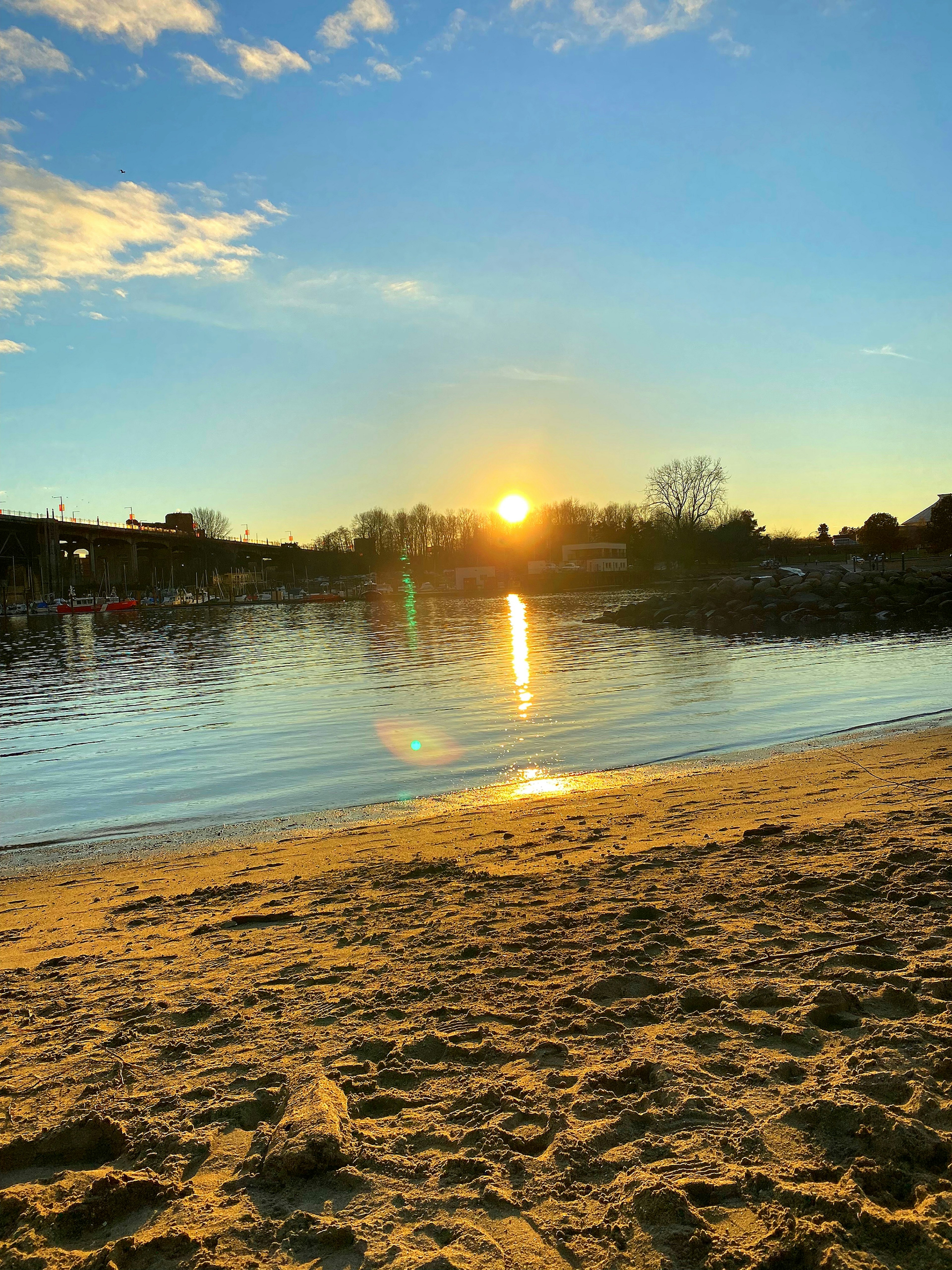 ทิวทัศน์ชายหาดที่เงียบสงบพร้อมการสะท้อนของพระอาทิตย์ตกบนผืนน้ำ