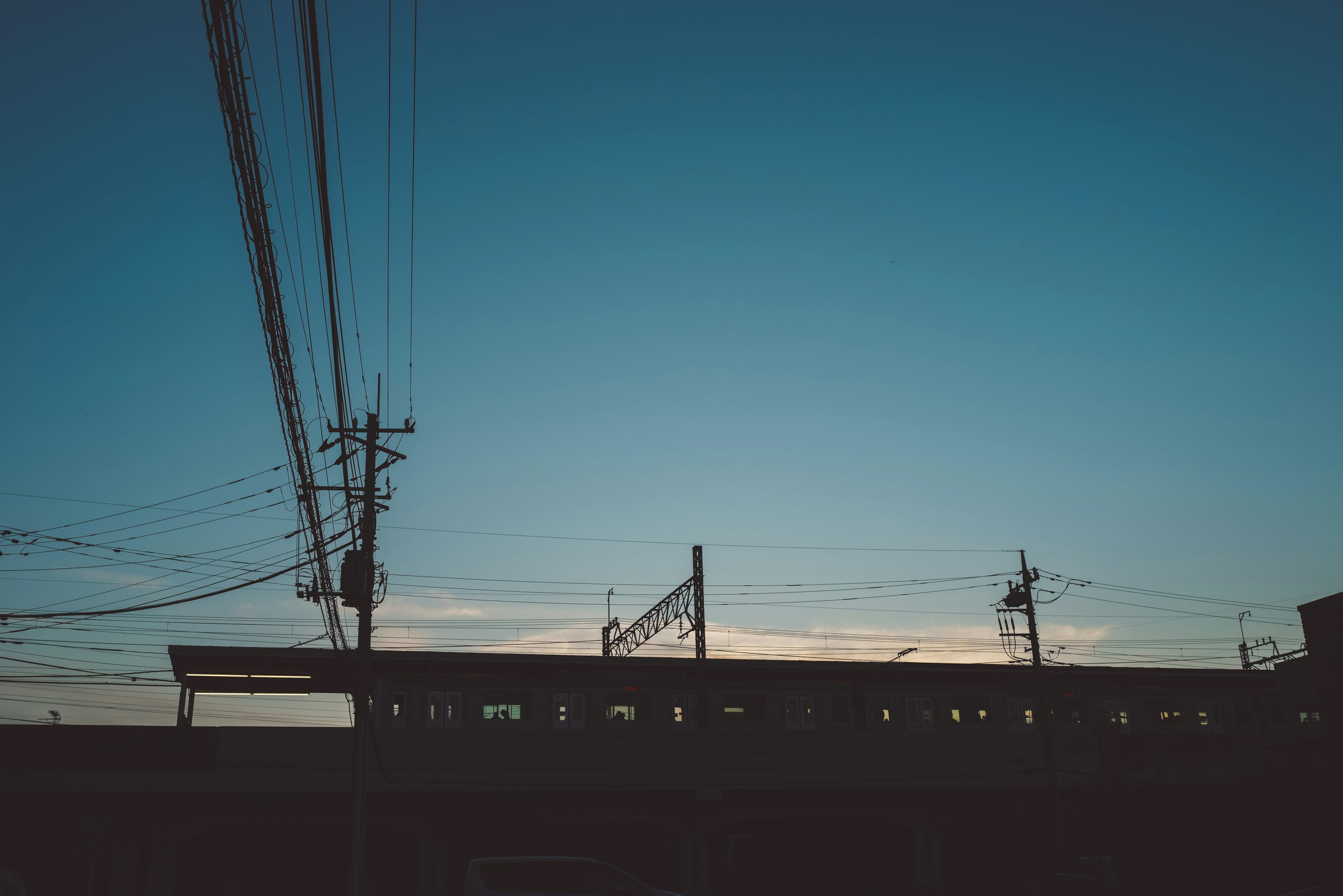 夕焼けの空を背景にした電車のシルエットと電線