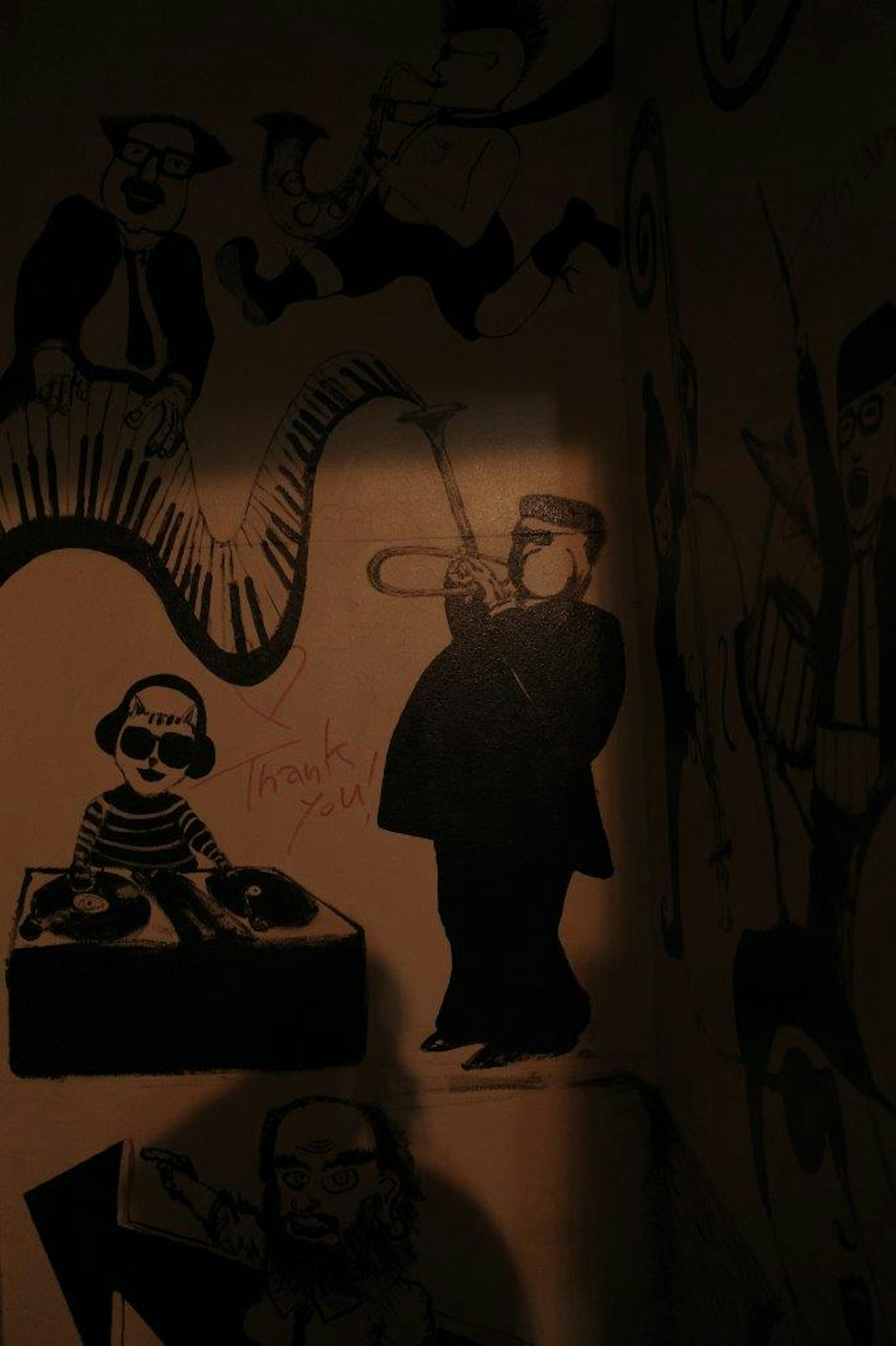 Silhouette noire d'un musicien jouant de la trompette avec une figure de DJ dans une fresque