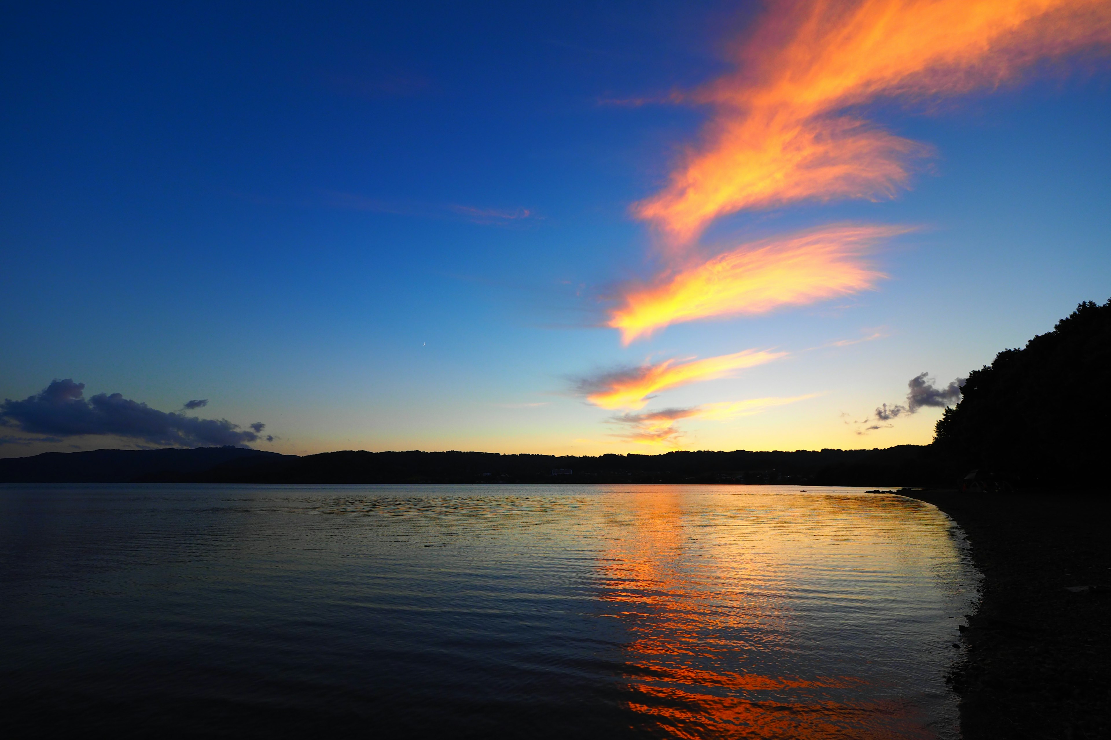 Beaux nuages orange se reflétant sur l'eau au coucher du soleil