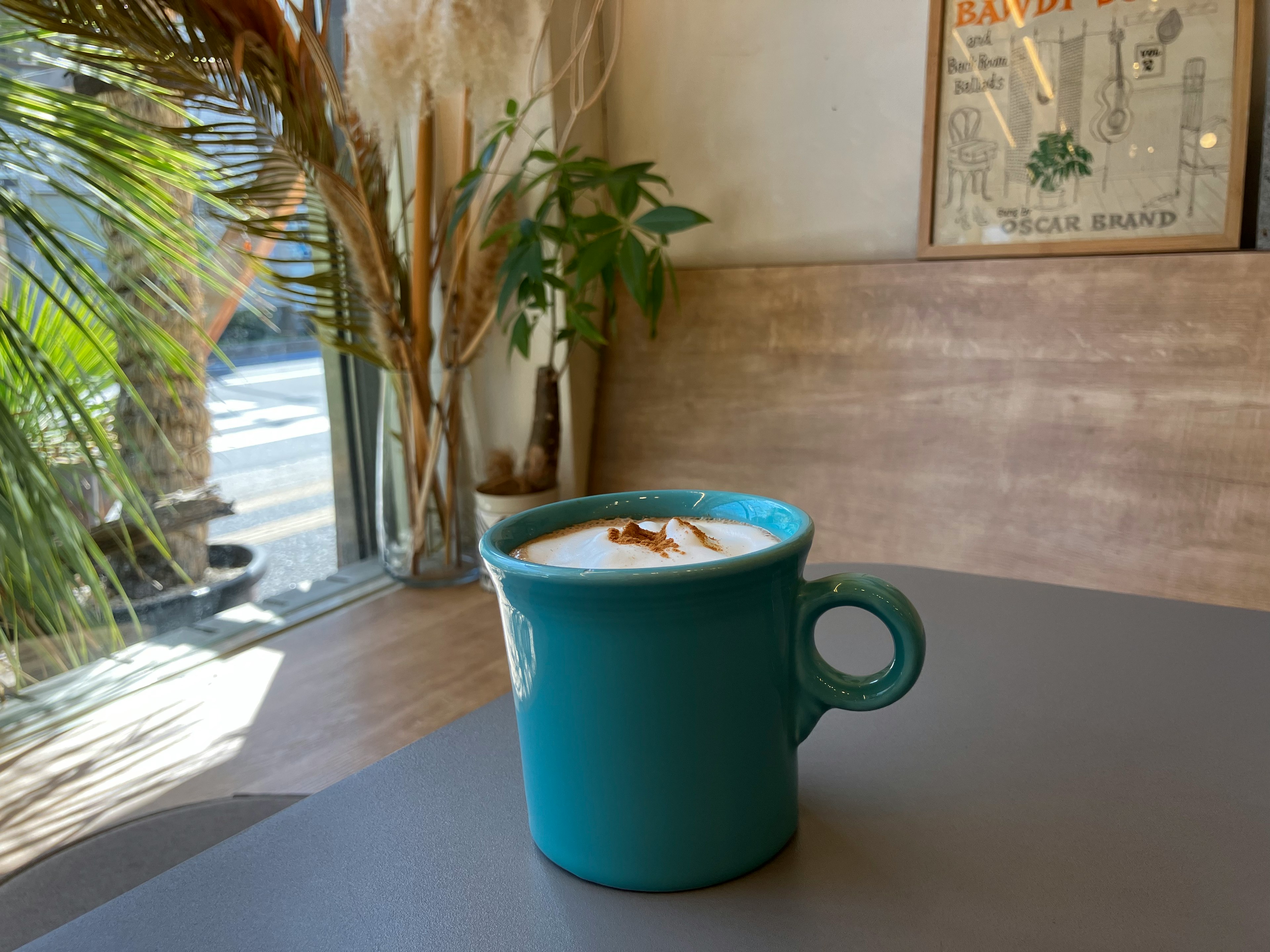 緑のカップに入ったコーヒーがテーブルに置かれたカフェの風景