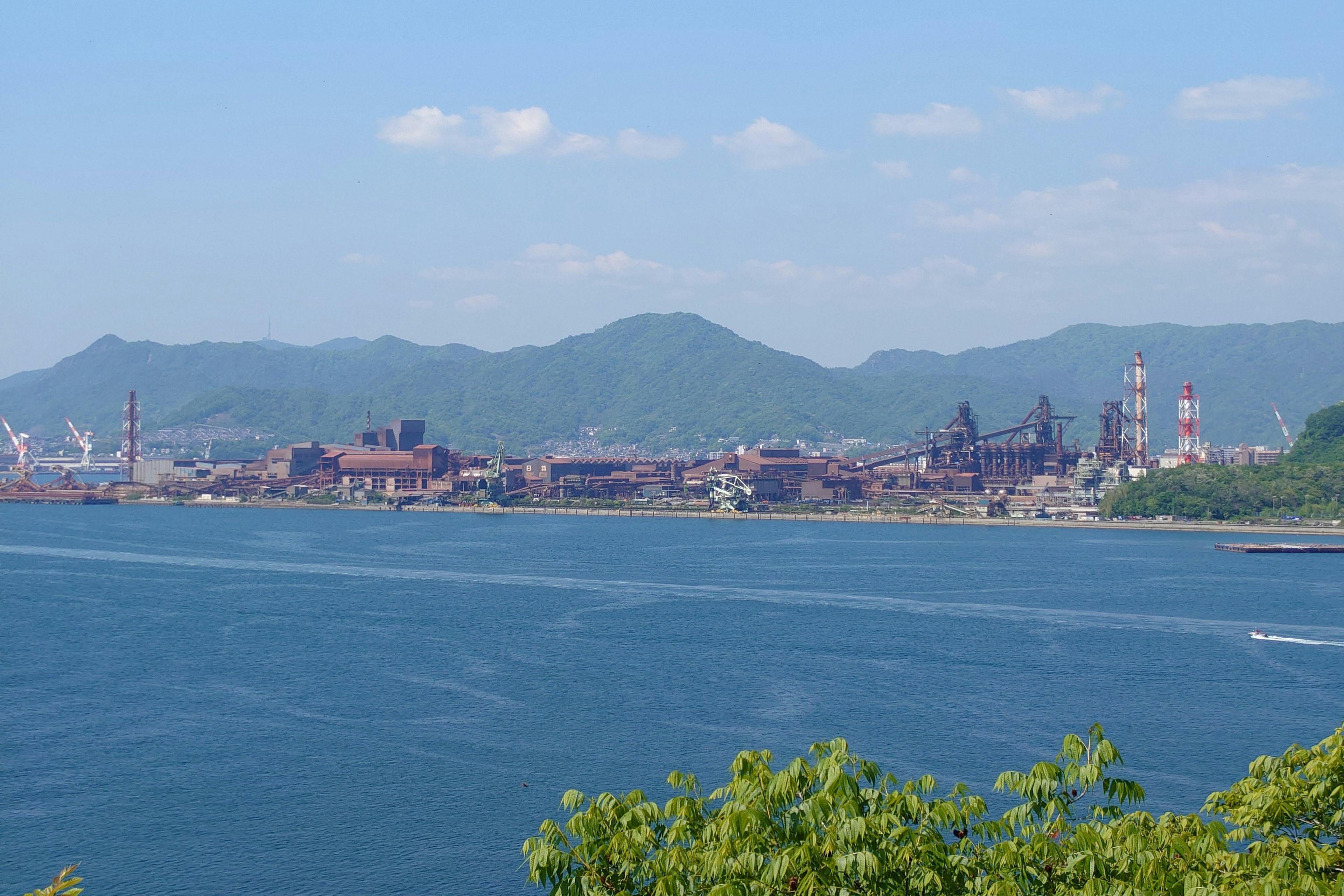 Vista panoramica dell'oceano blu e dell'area industriale con montagne sullo sfondo