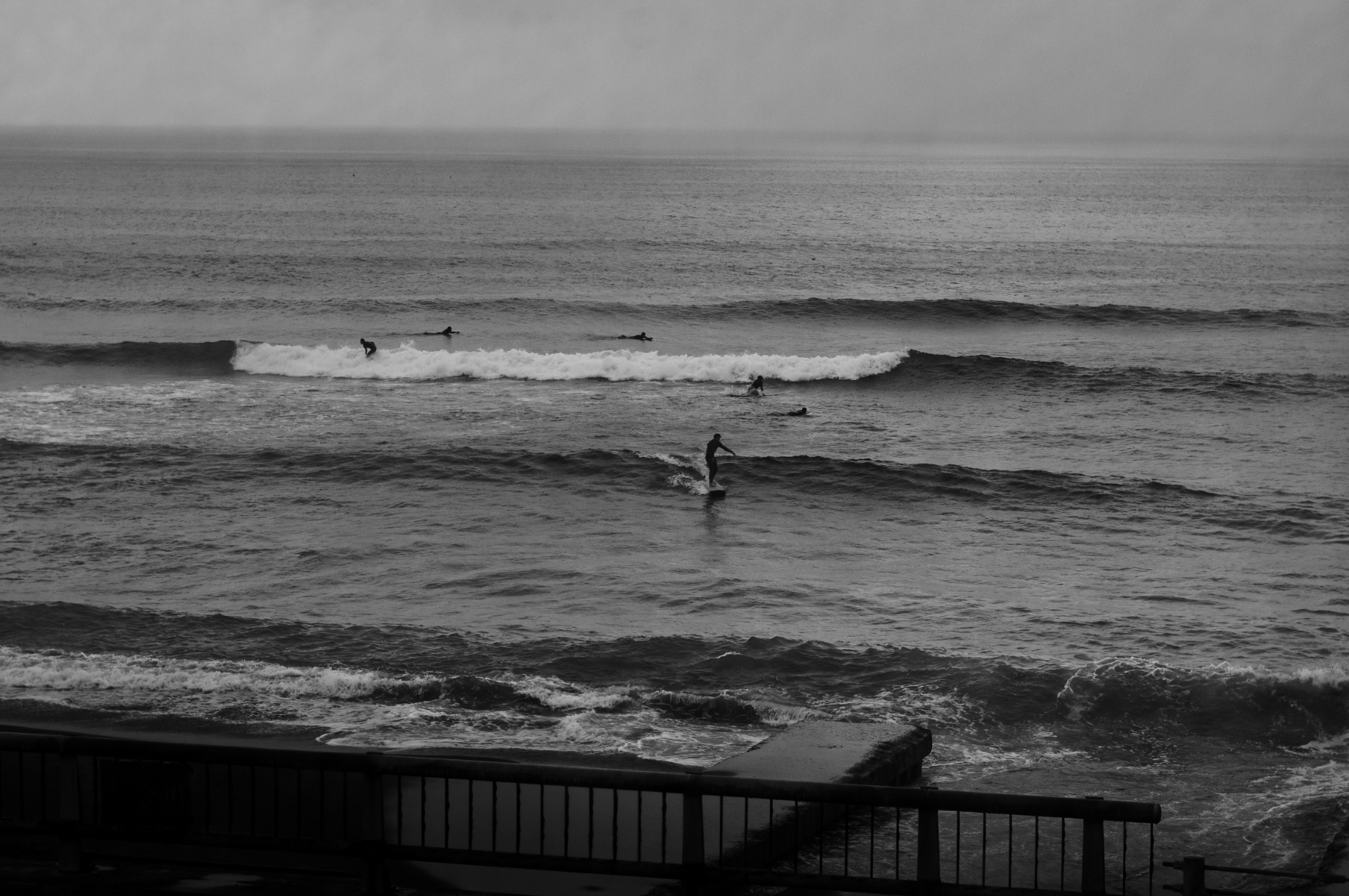 海でサーフィンをする人がいるモノクロの風景