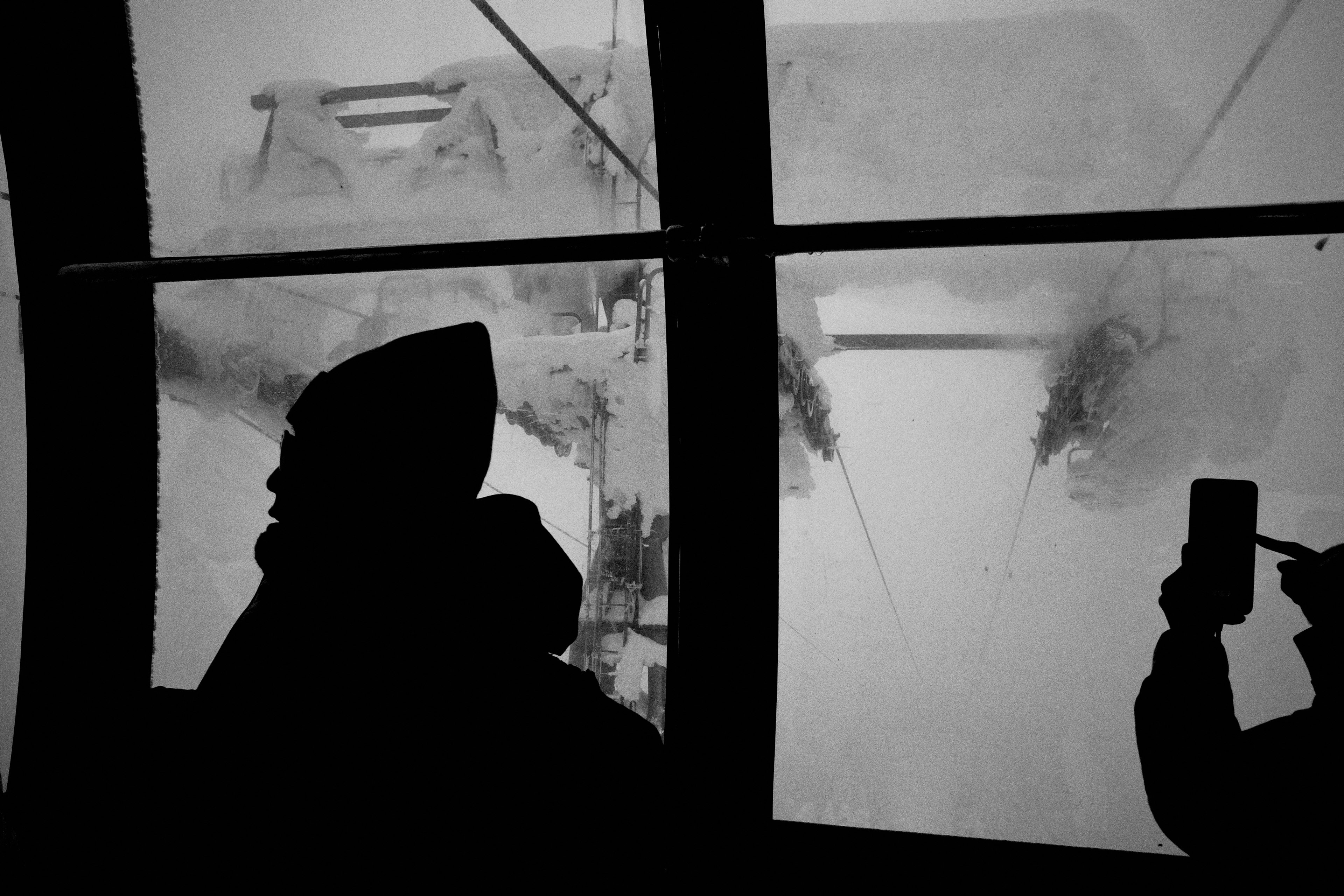 Silhouette einer Person in einer Seilbahn mit schneebedeckten Bergen draußen