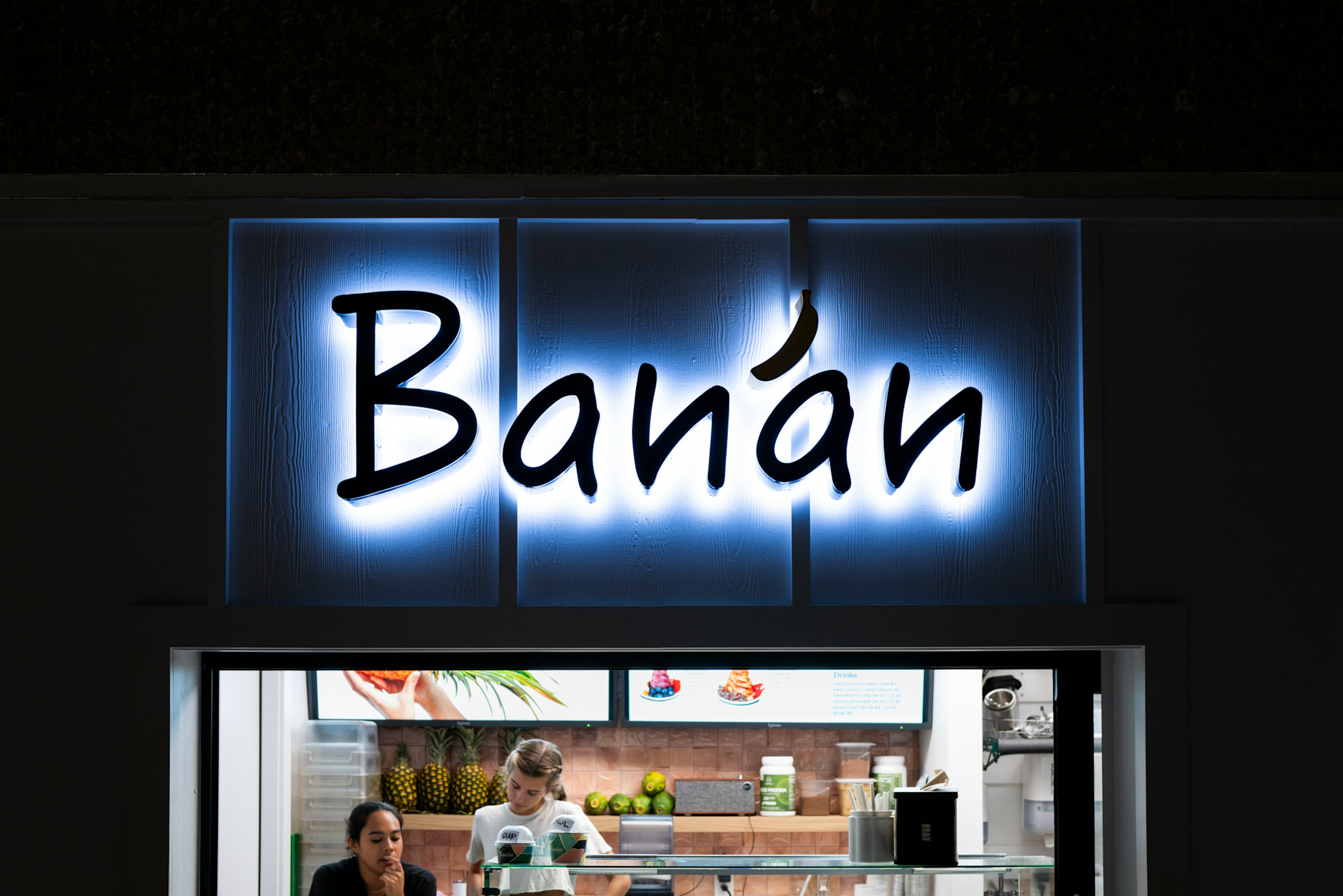 商店外觀有霓虹燈牌Banán兩名員工在裡面可見