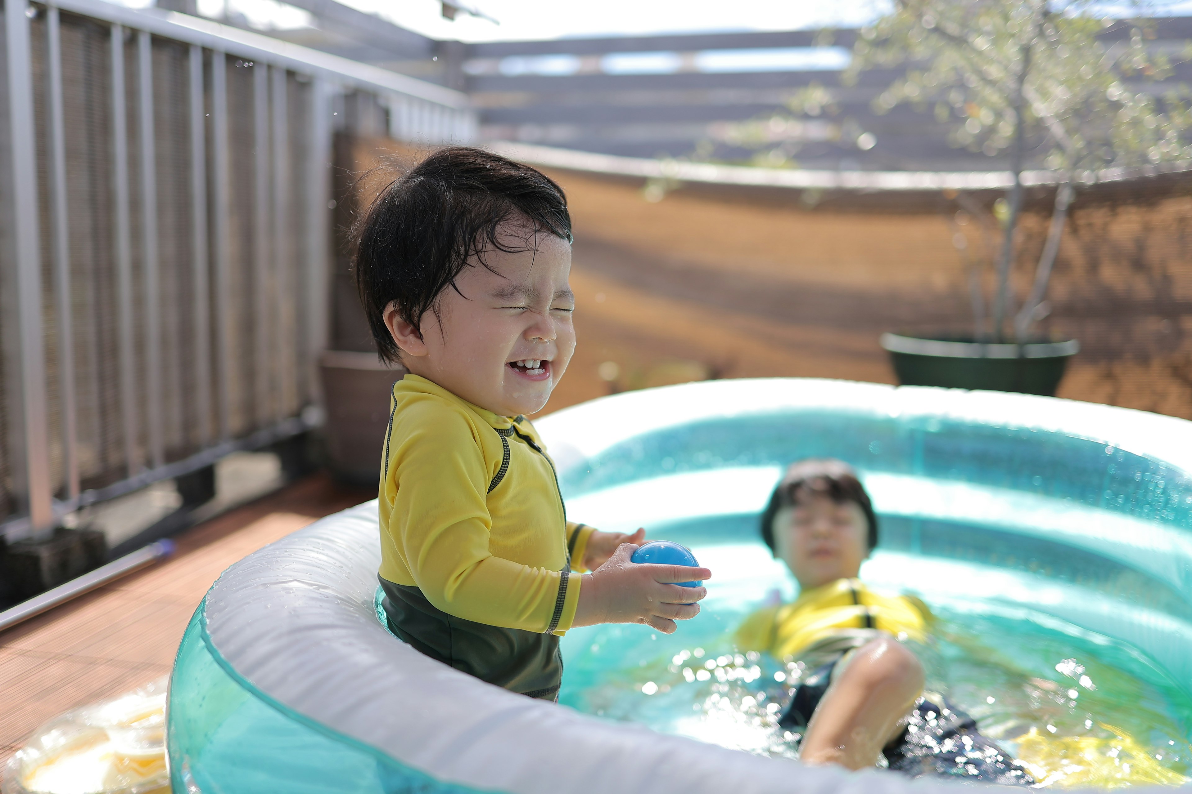 Bambino che gioca in una piscina con un altro bambino che si rilassa