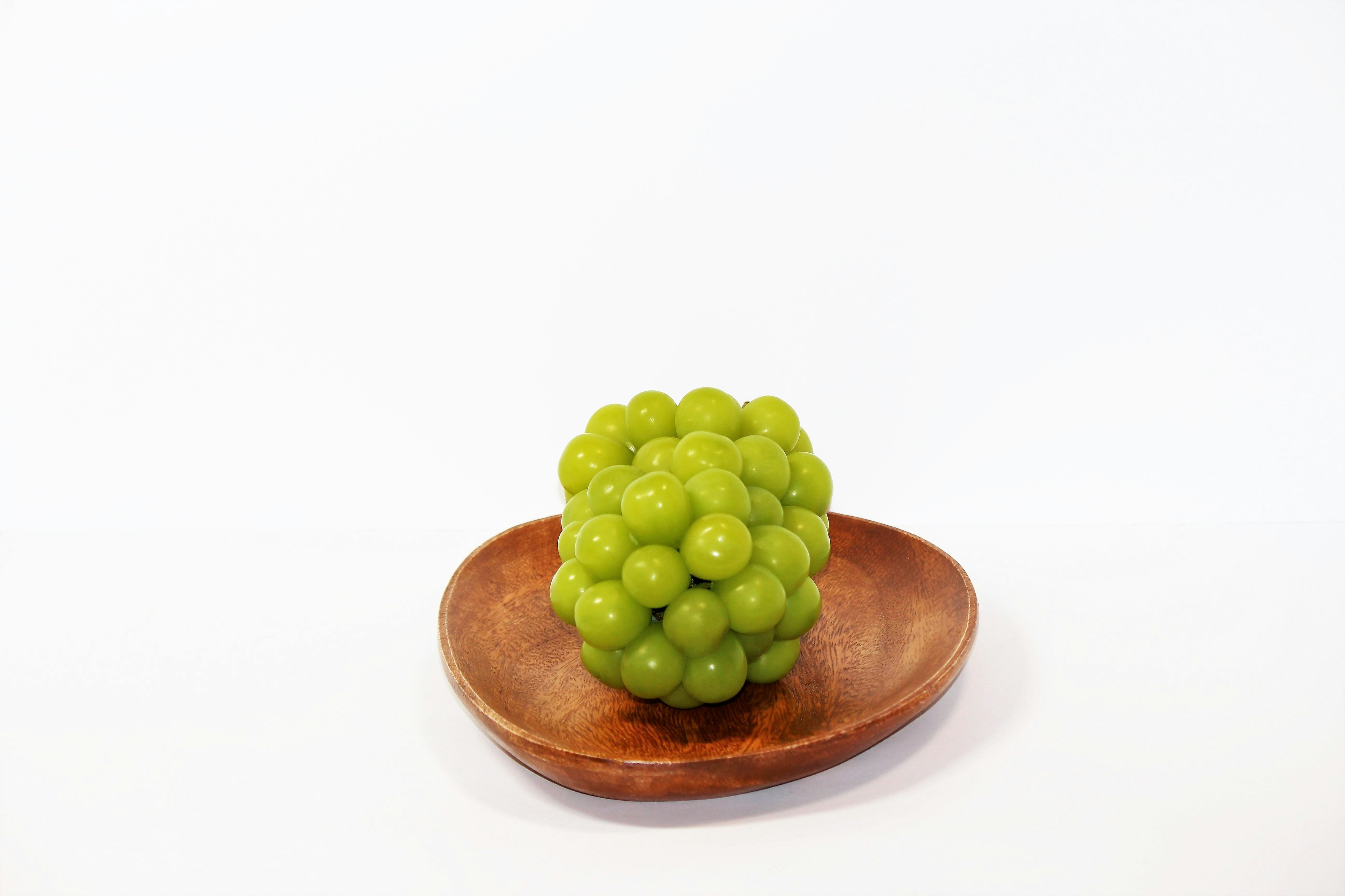 A green grape-like object placed on a wooden plate