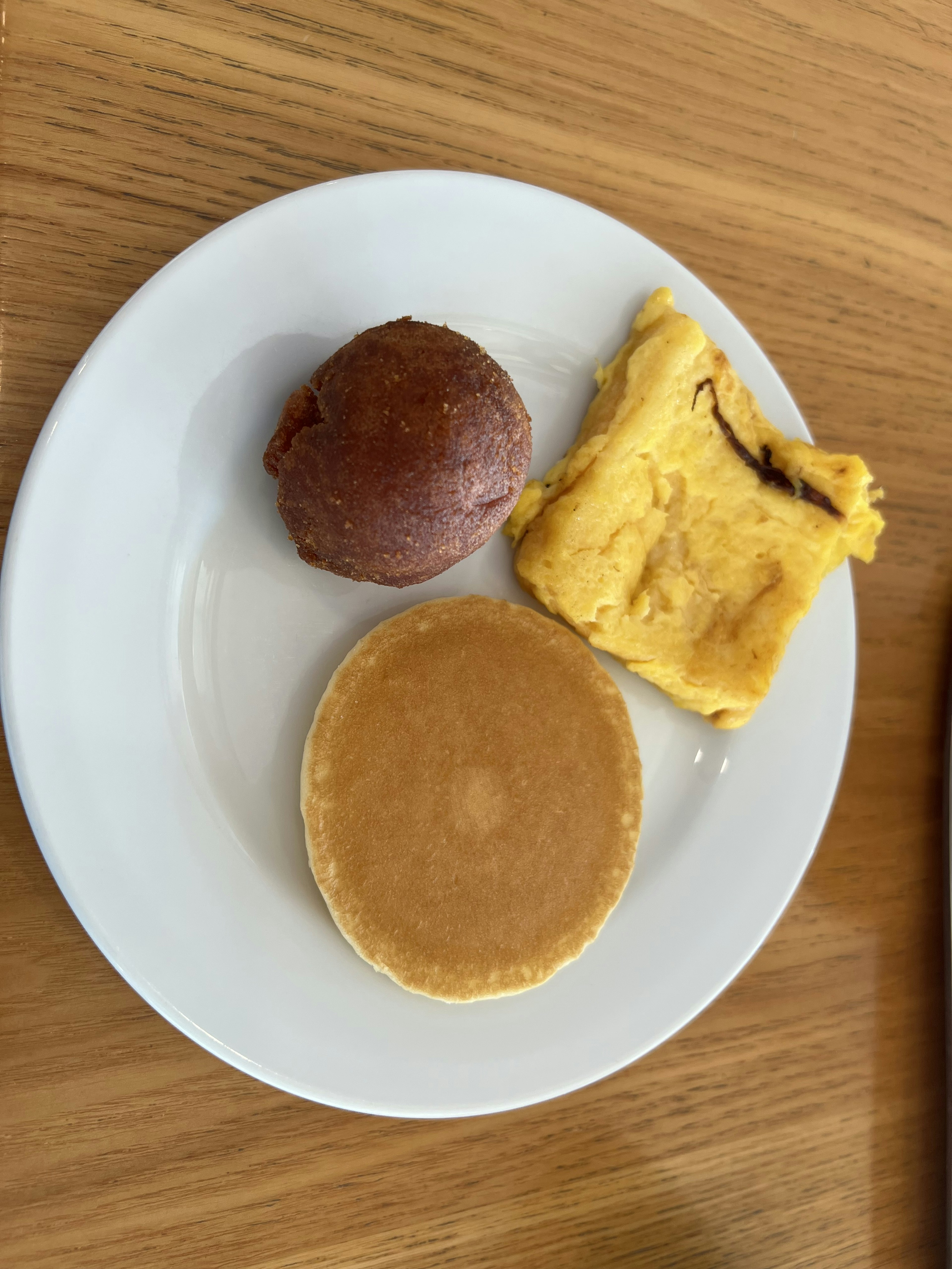 Ein Teller mit einem Pfannkuchen, einem gelben Ei-Gericht und einem roten Gebäck