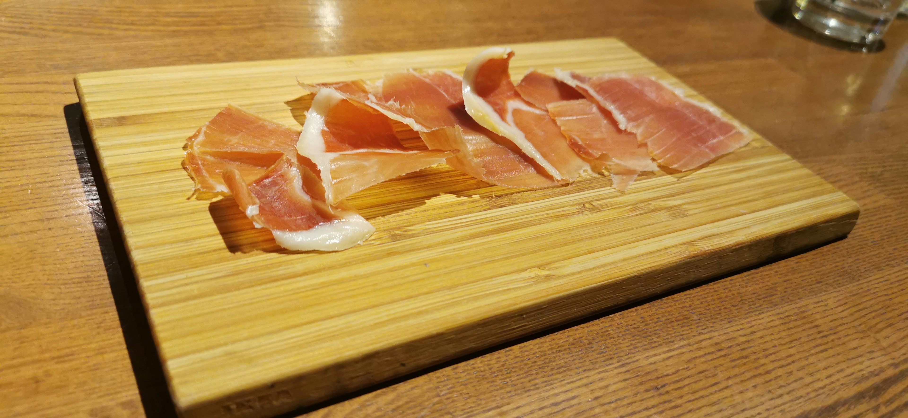 Scheiben von Jamón Serrano auf einem Holzbrett angeordnet