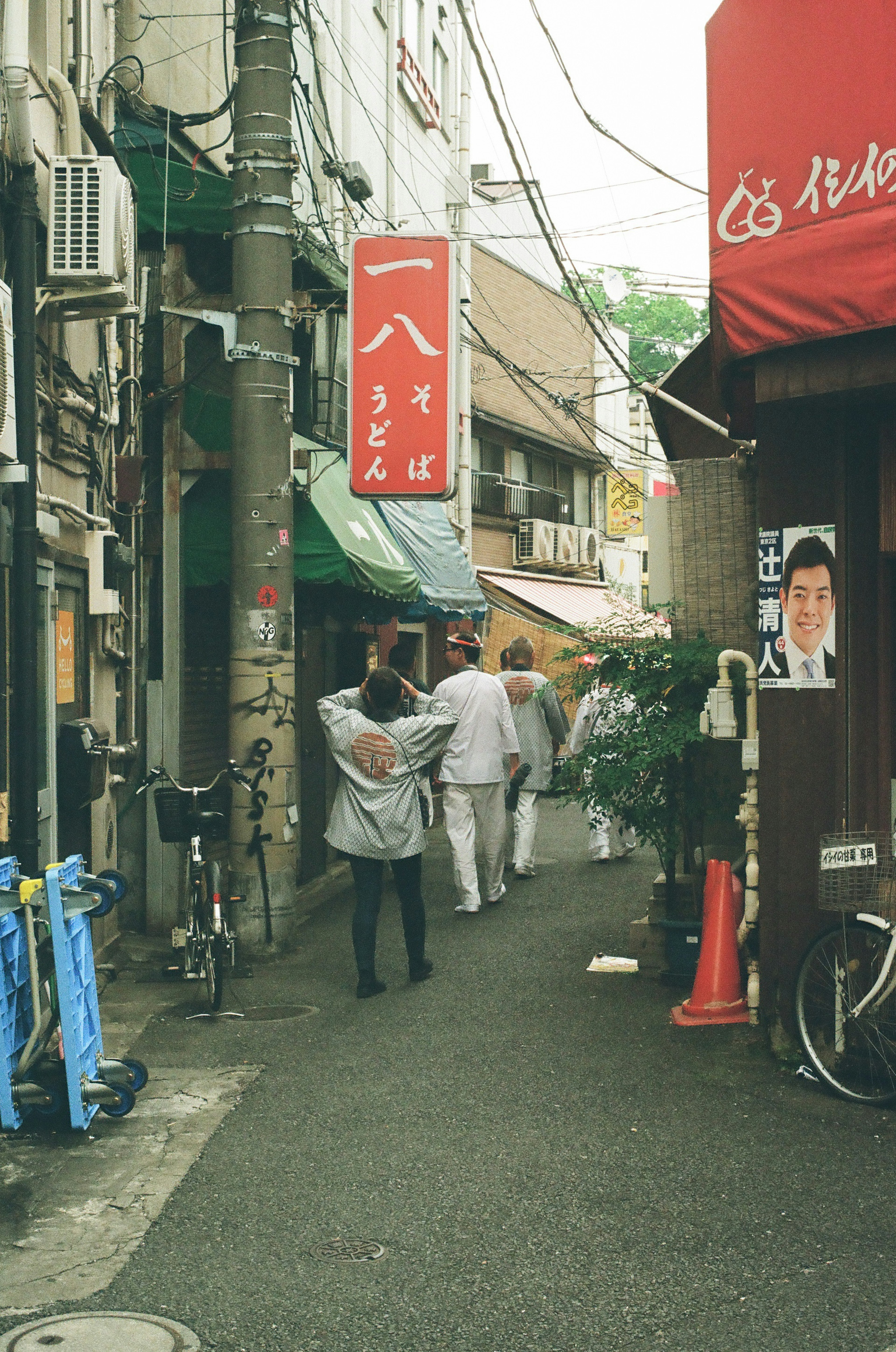 狭い路地にある赤い看板の店と人々が歩いている風景