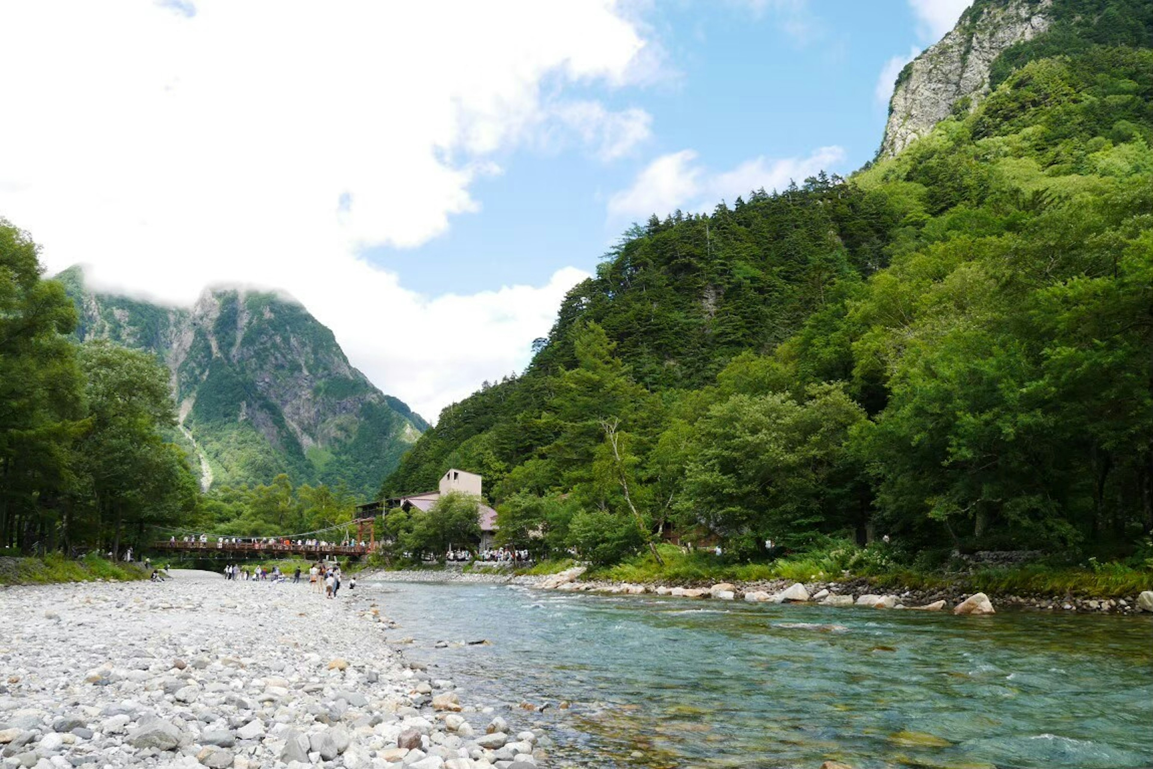 翠綠山脈和河流的風景，有人們在散步