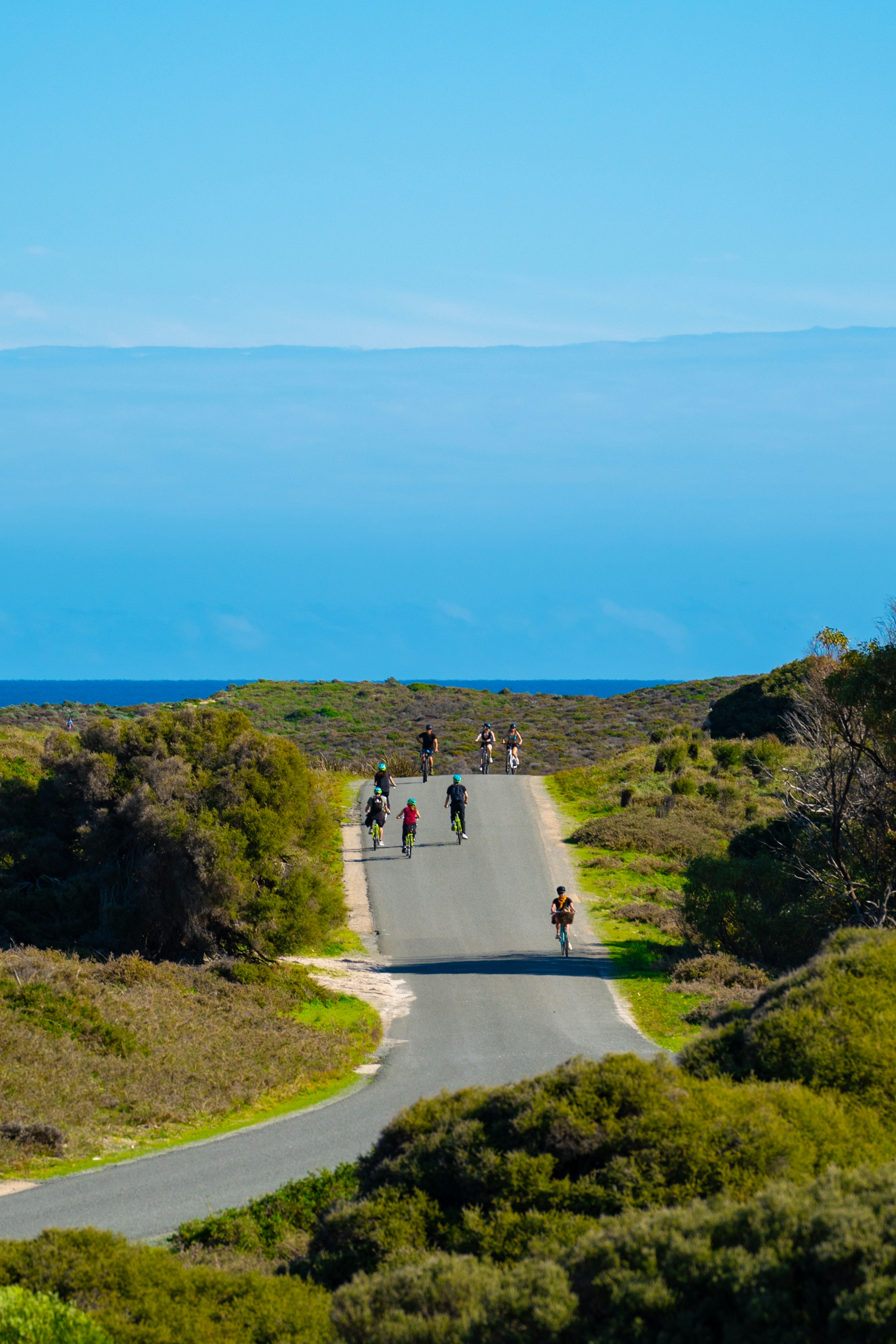 青い海と広い空の下で人々が歩く道路の風景