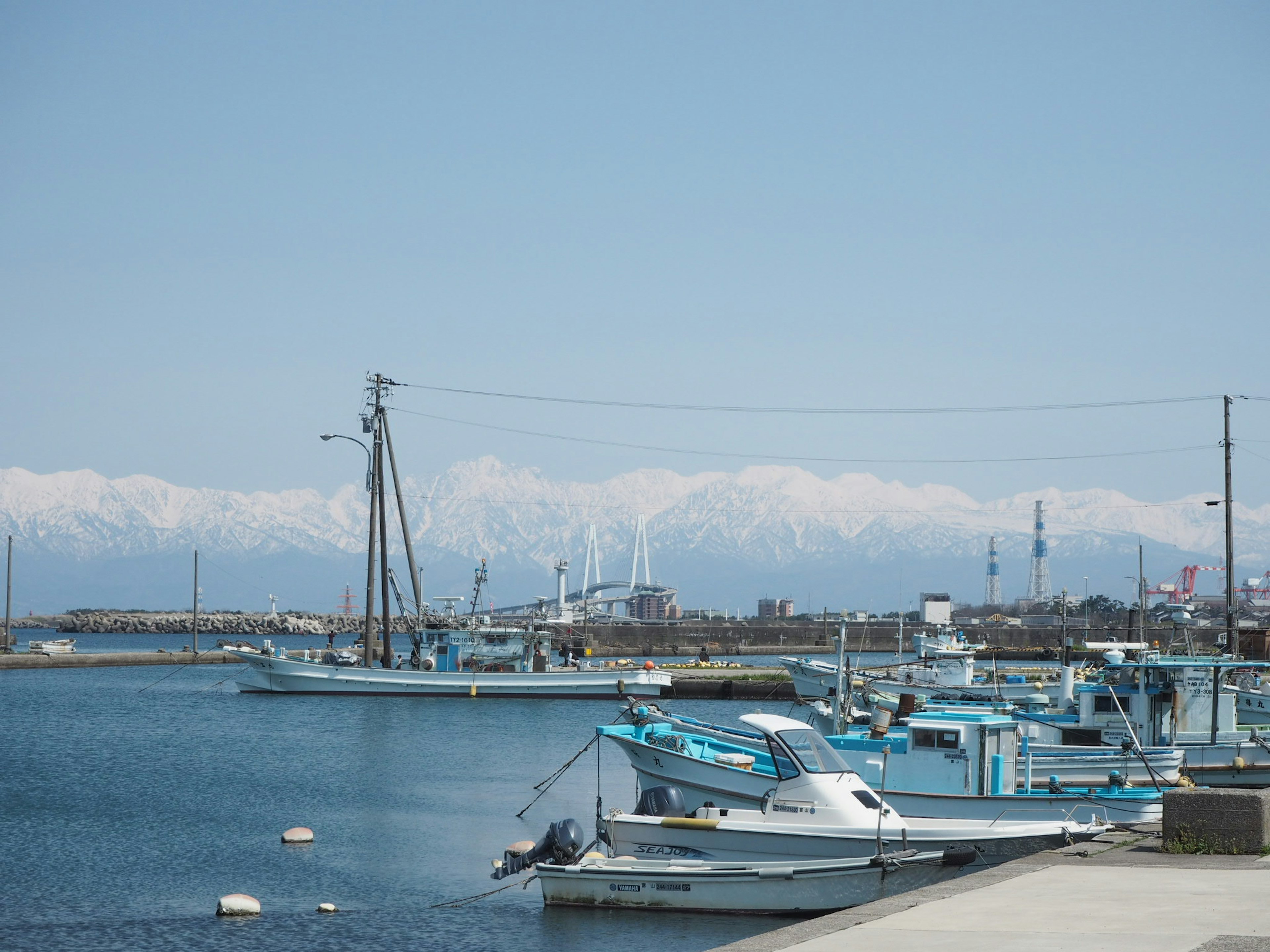 Scena di porto tranquilla con barche da pesca e montagne innevate sullo sfondo