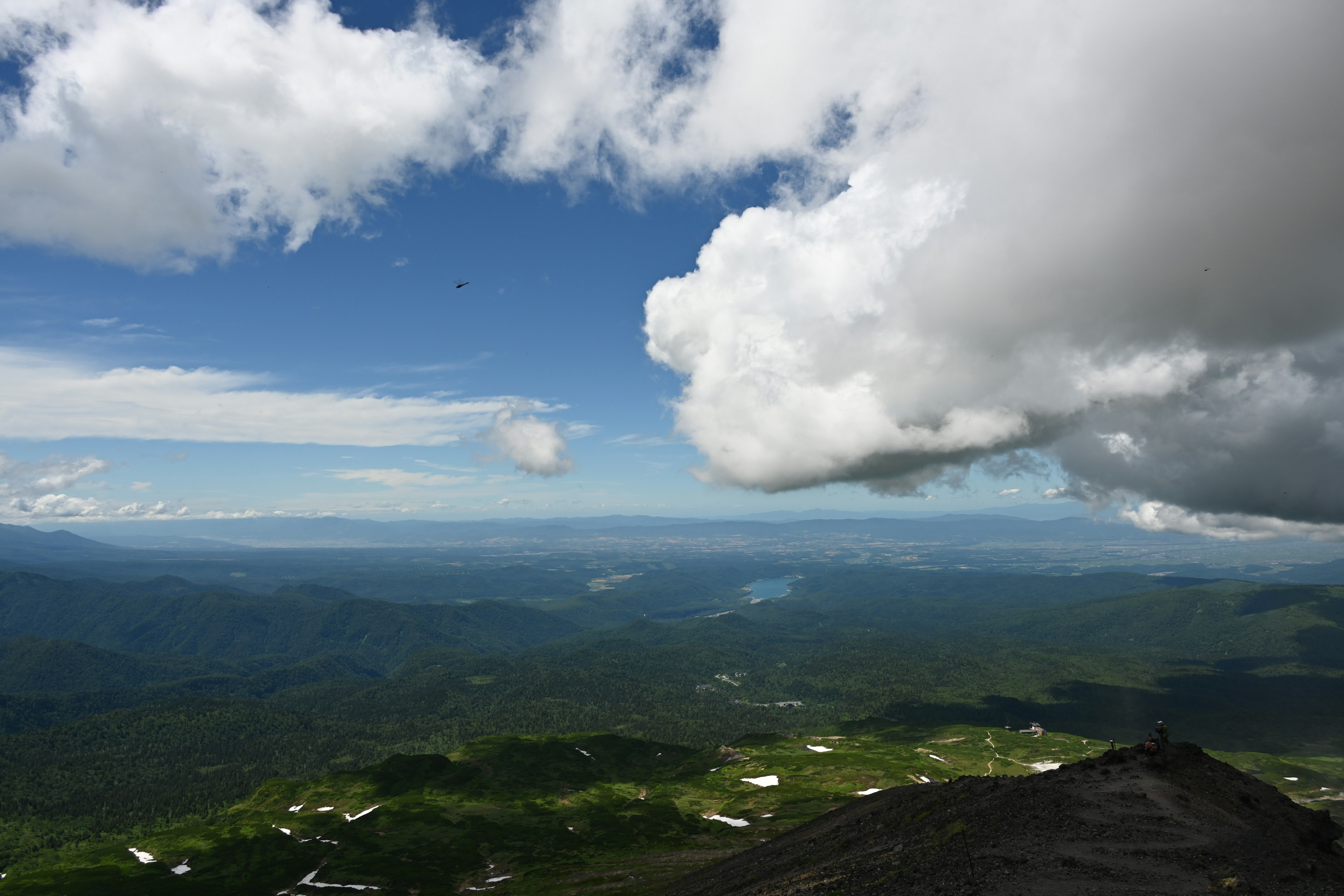 Impresionante vista desde la cima de una montaña con cielo azul y nubes blancas sobre vegetación exuberante