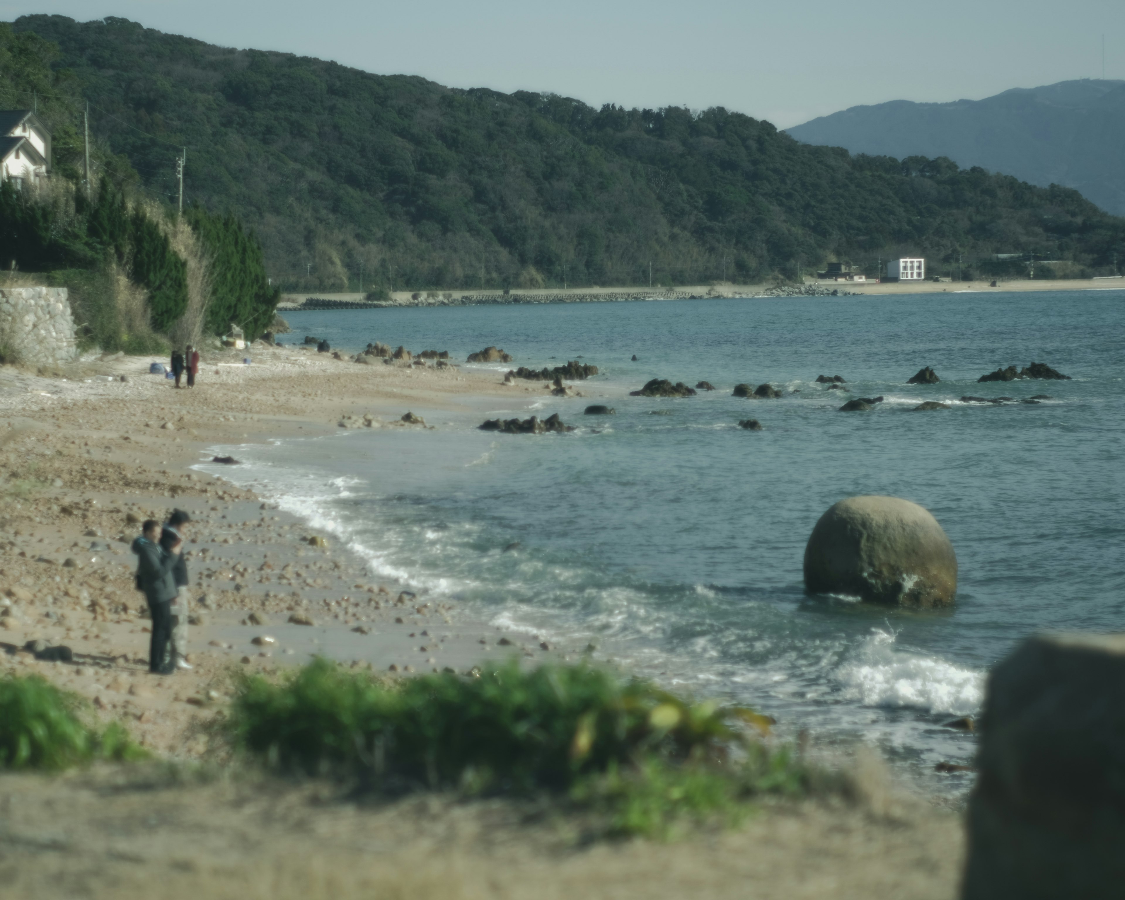 Pemandangan pantai tenang dengan ombak pantai dan batu besar