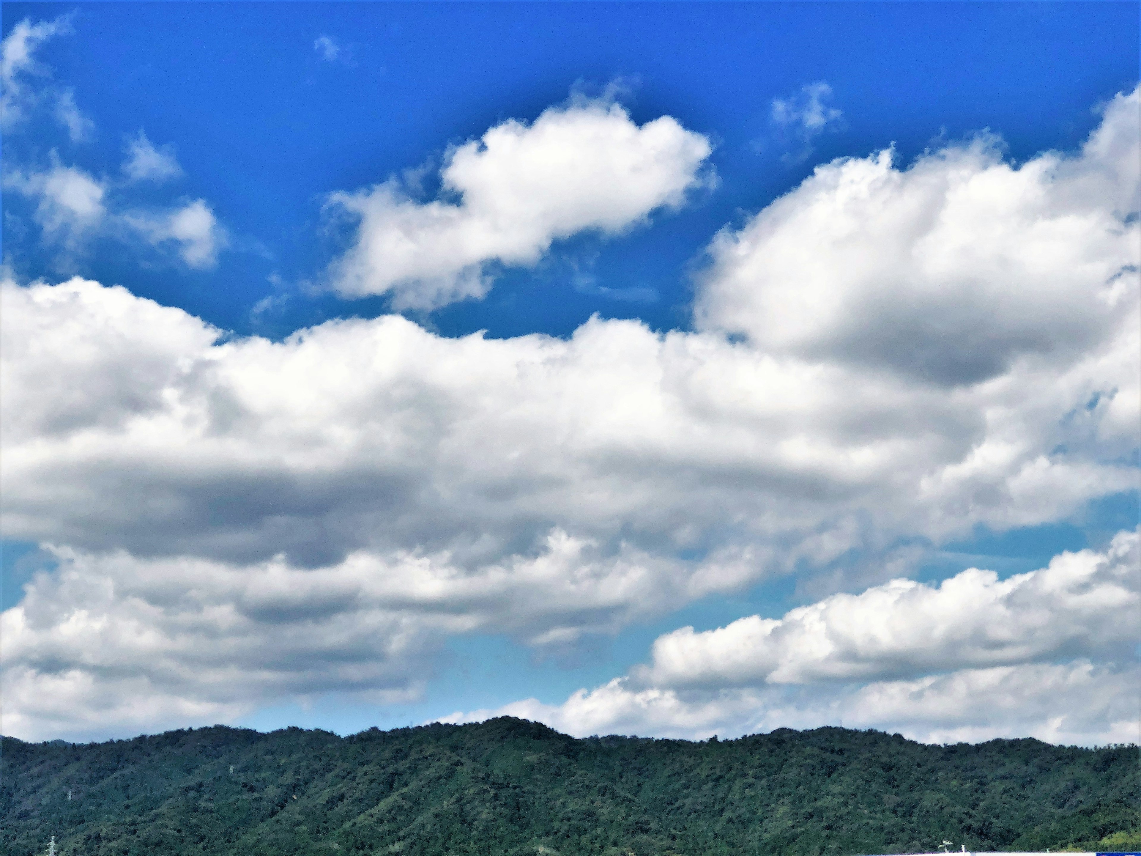 青空と白い雲が広がる山の風景