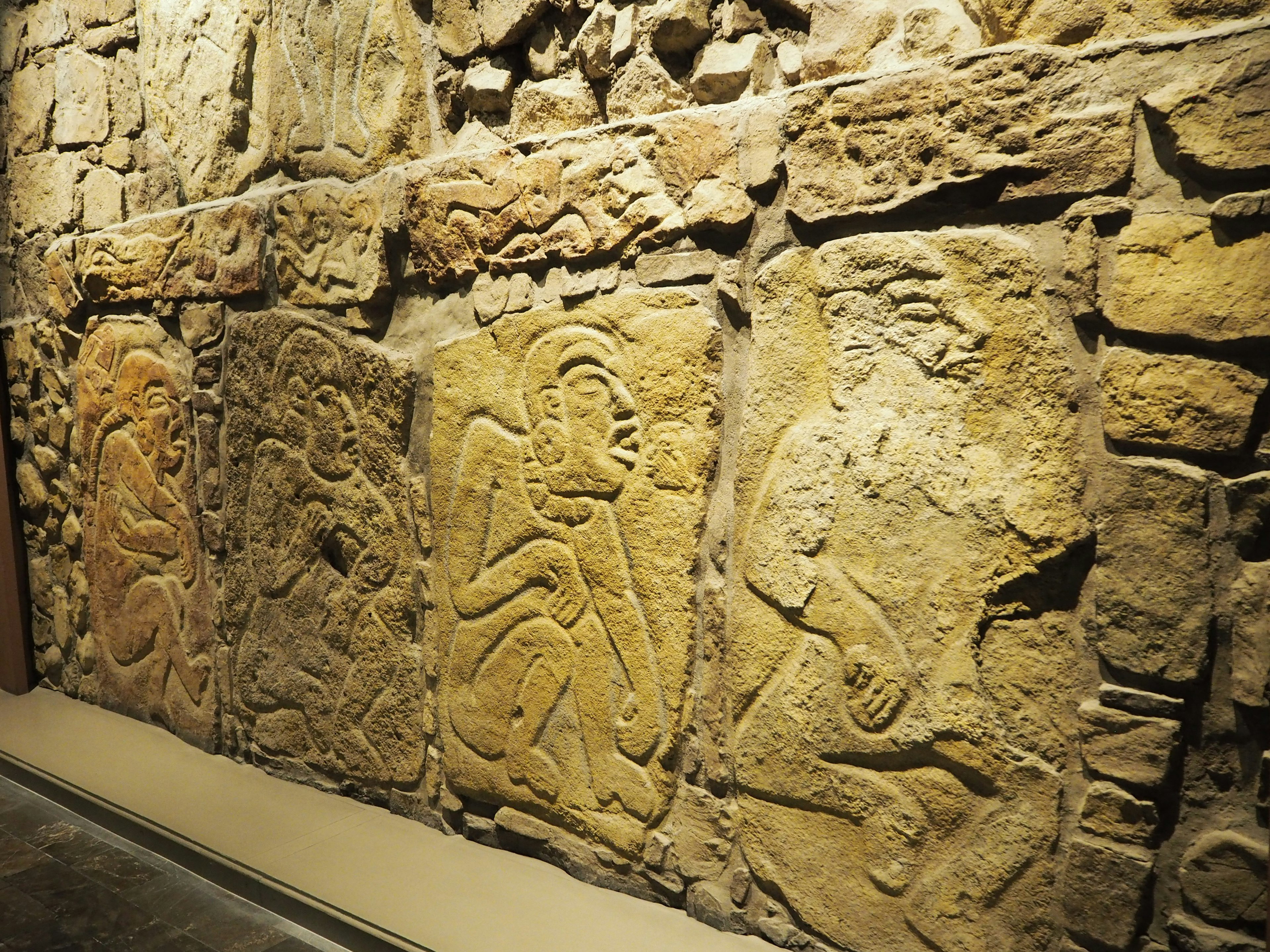 Sculptures anciennes sur un mur en pierre représentant plusieurs figures humaines