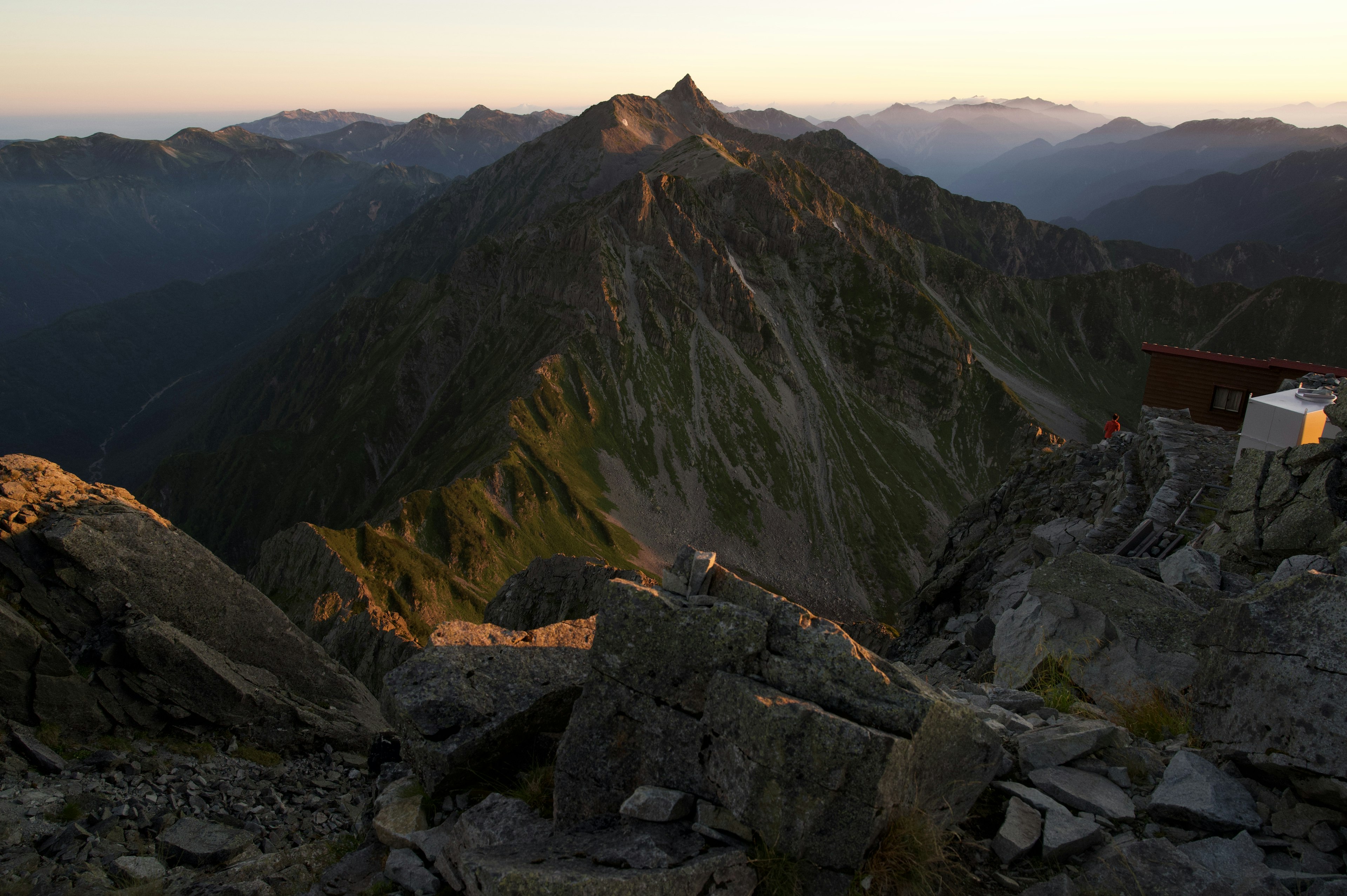 Vue panoramique depuis un sommet de montagne avec le coucher de soleil illuminant les crêtes