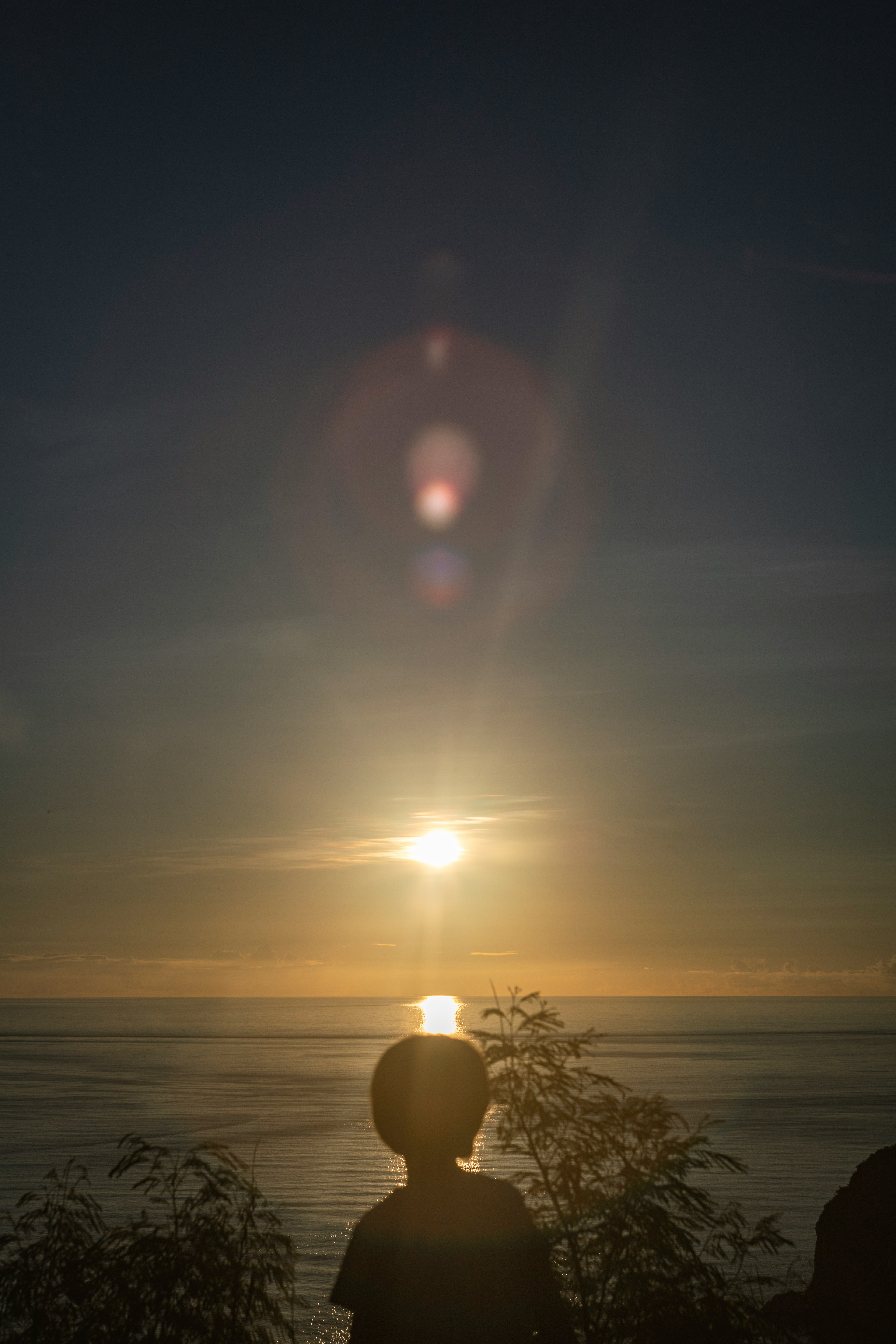 夕日を背にした子供のシルエット 海の上に広がる光の反射