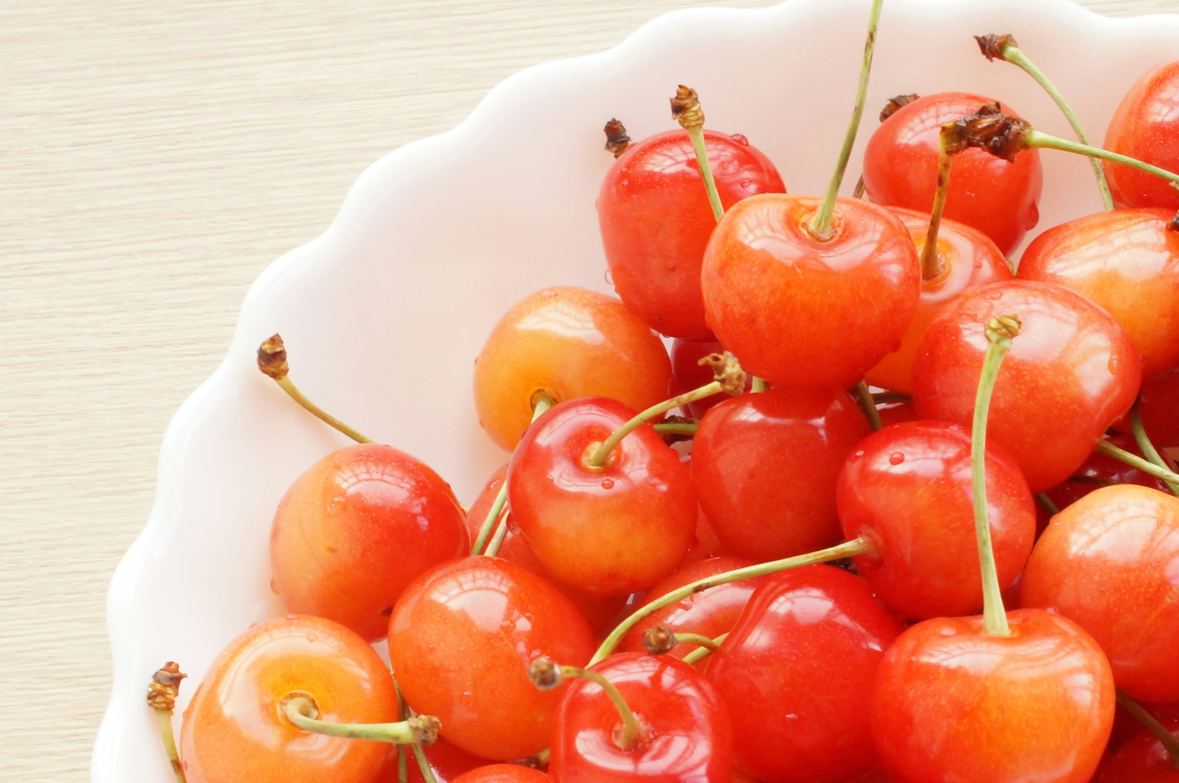 Vivid red and orange cherries arranged in a white bowl