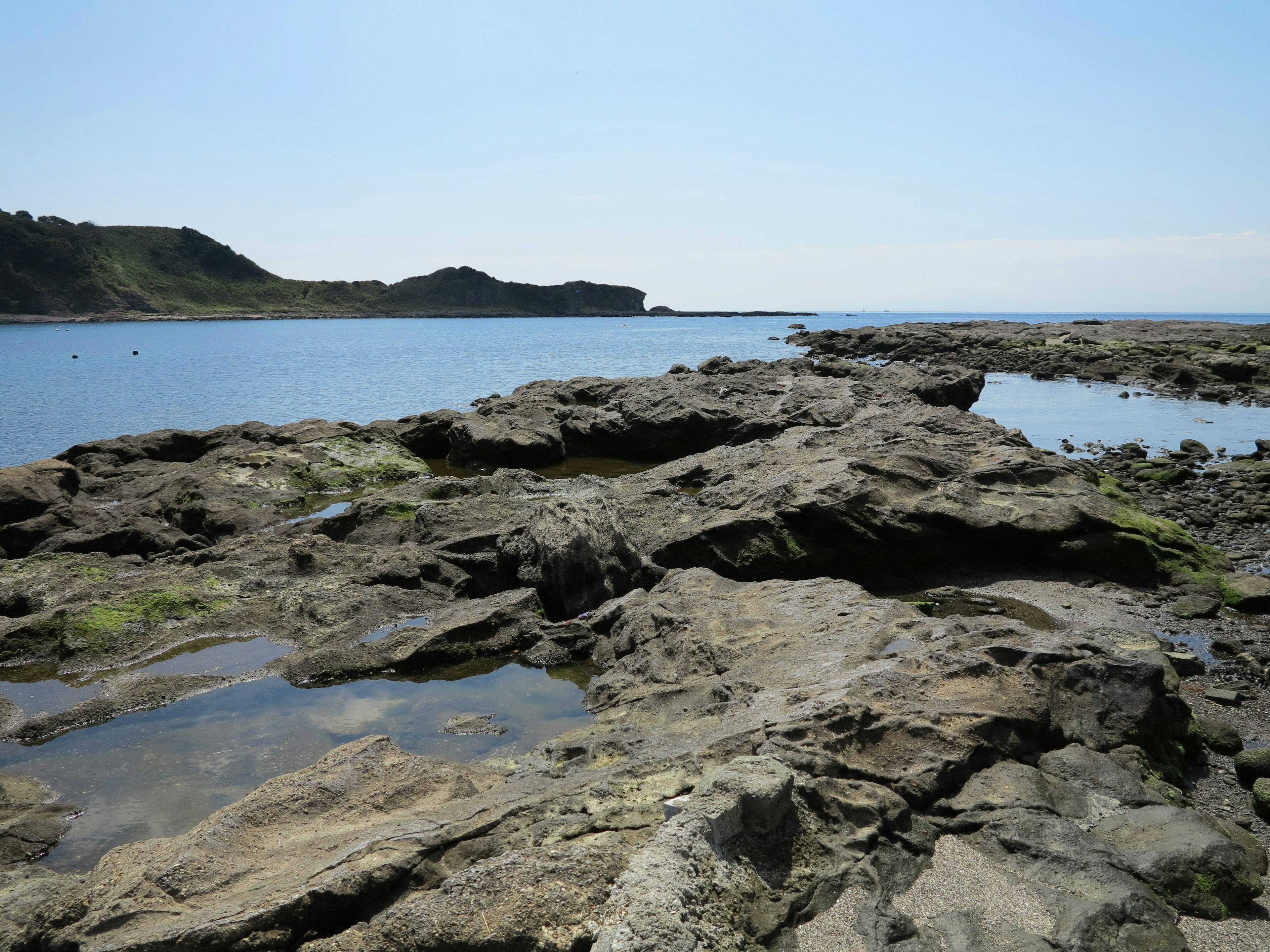 Mar tranquilo y paisaje rocoso con musgo verde en las rocas