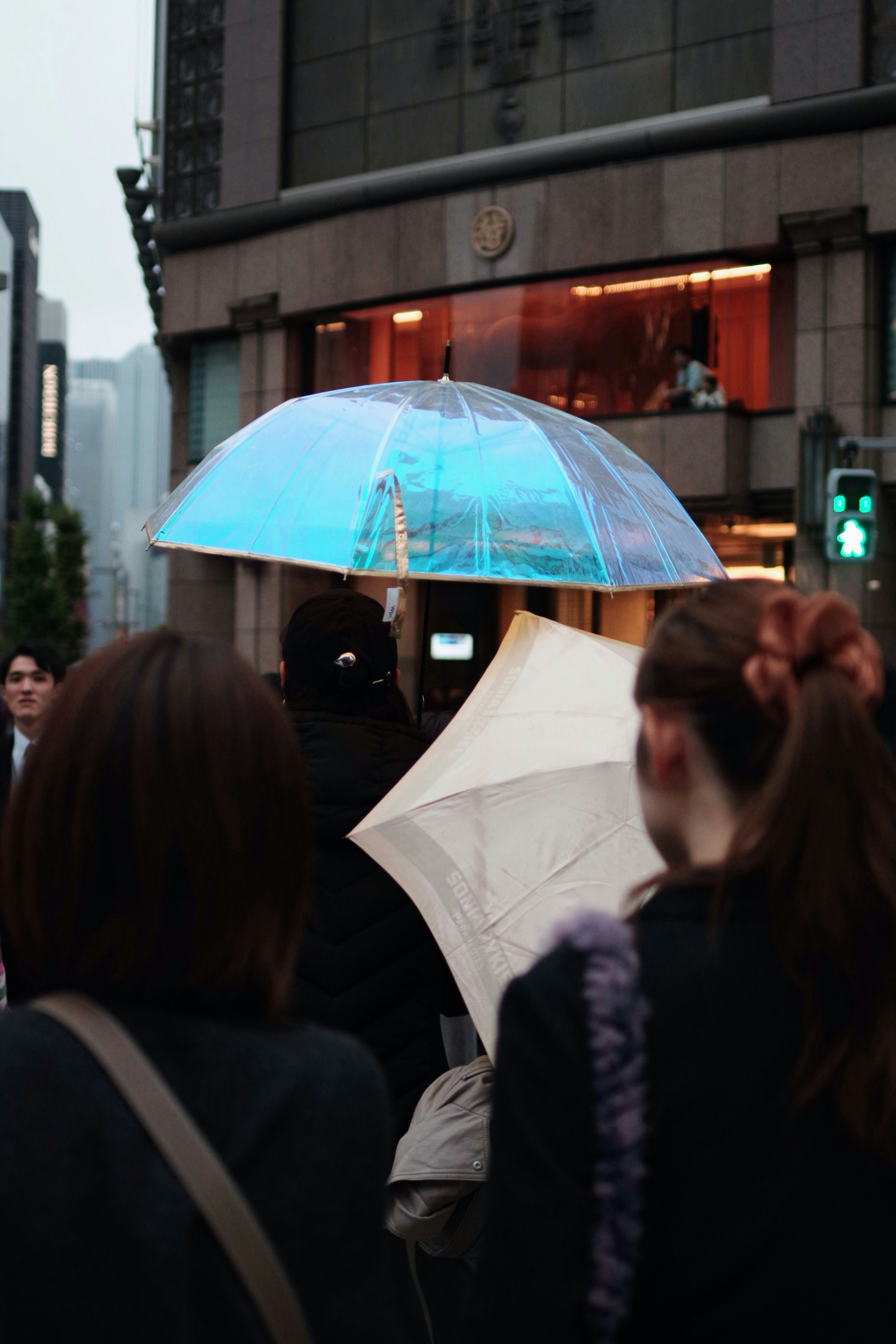 青い傘を持つ人々が歩く都市の風景